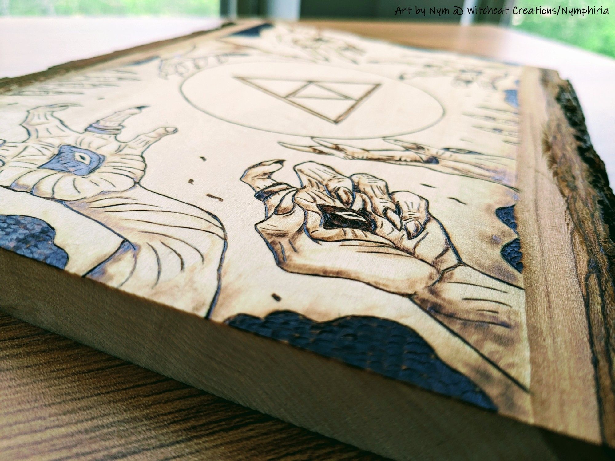 a photo of a pyrography piece with a triforce holding back gloomhands and darkness with radiant light