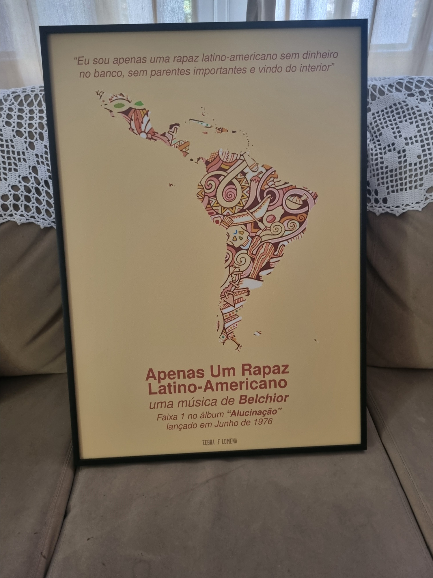 Quadro com o mapa da América Latina (América do Sul, Central e México) sob um fundo amarelo e os versos da música Apenas Um Rapaz Latino-Americano "Eu sou apenas um rapaz latino-americano sem dinheiro no banco, sem parentes importantes e vindo do interior". Os versos estão acima do mapa, e abaixo está o nome da música em negrito e a legenda "uma música de Belchior (também em negrito) - Faixa 1 no álbum"Alucinação" (em negrito) lançado em Junho de 1976.

Na parte inferior, está escrito ZEBRA FILOMENA