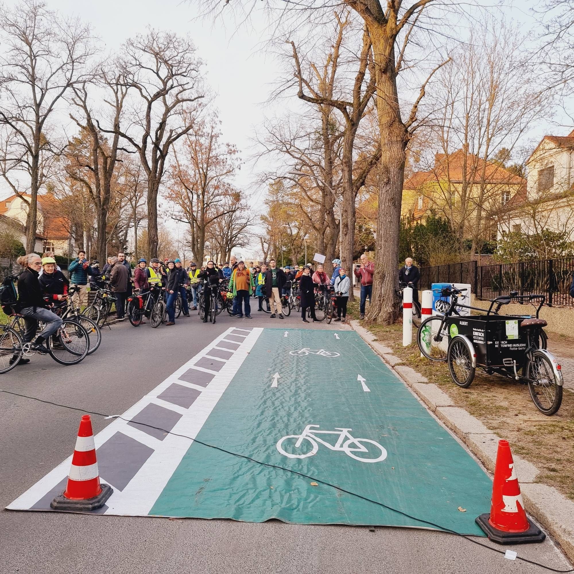 Fahrraddemonstratinnen, davor ausgerollter grüner Fahrradteppich mit links und rechts 2 Warnhütchen auf der Thielalle in Berlin