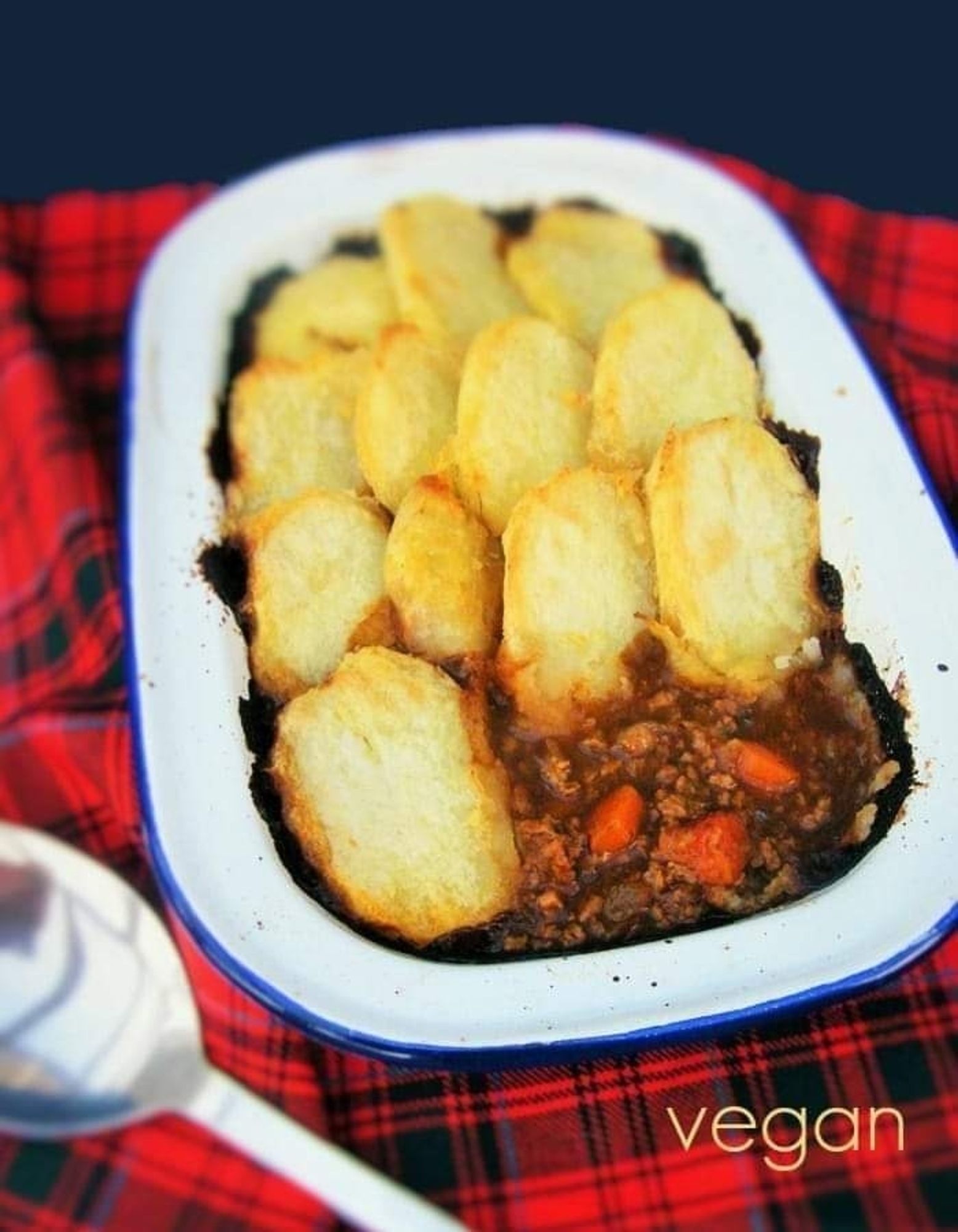 Cottage Pie topped with sliced potatoes in an enamel pie dish.