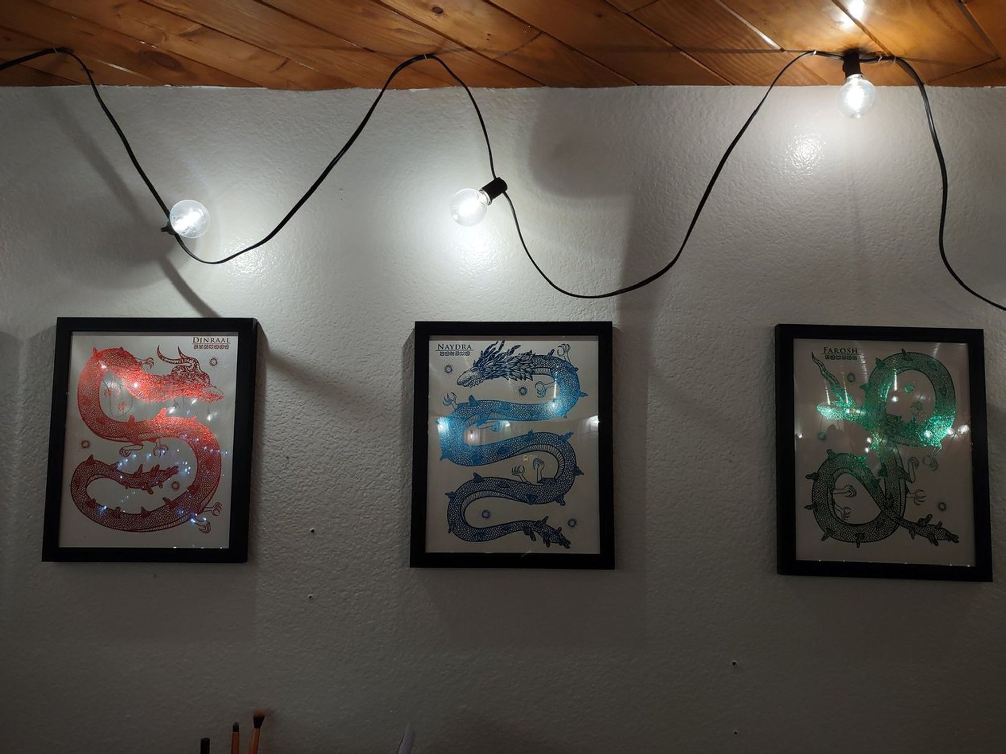 Bedroom wall, with framed foil artwork of Dinraal, Naydra, and Farosh.