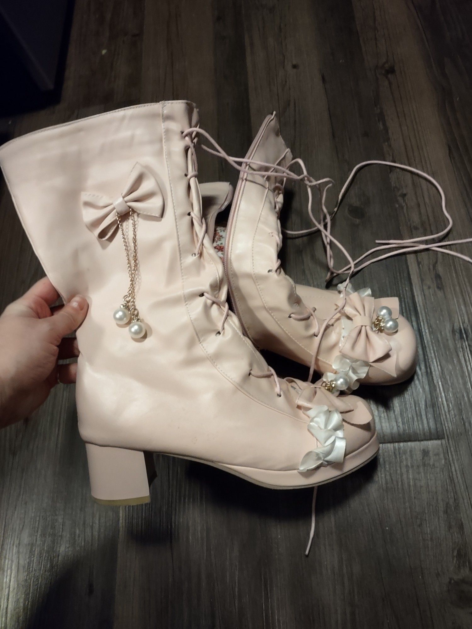 a pair of pale pink, mid-calf boots decorated with bows, frilly lace, gold chains, and faux pearls. they are AMAZING 