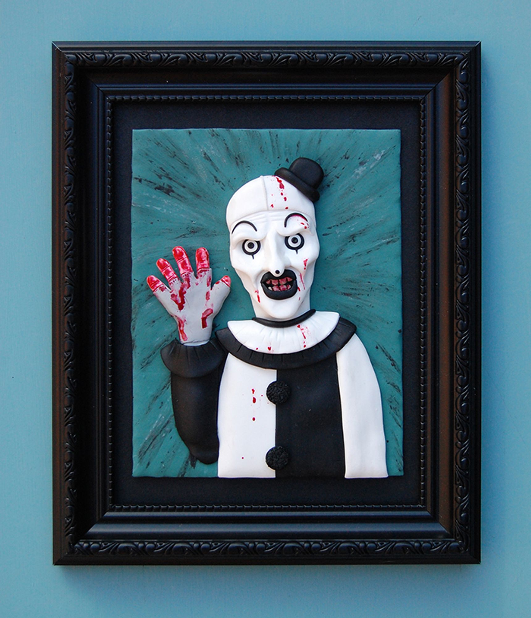 My polymer clay painting of Art the Clown of the Terrifier movies in a shabby frame