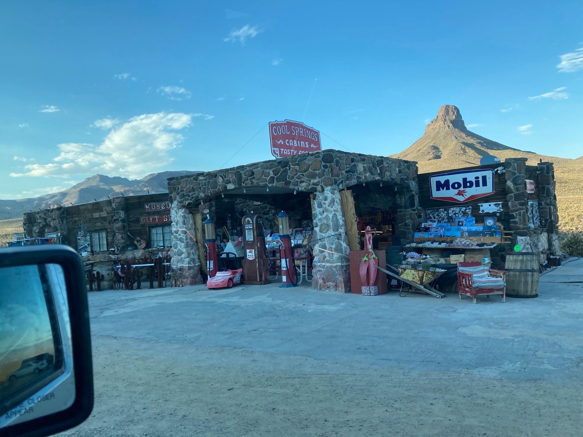 A stone building, once a gas station, cluttered with vintage advertising.