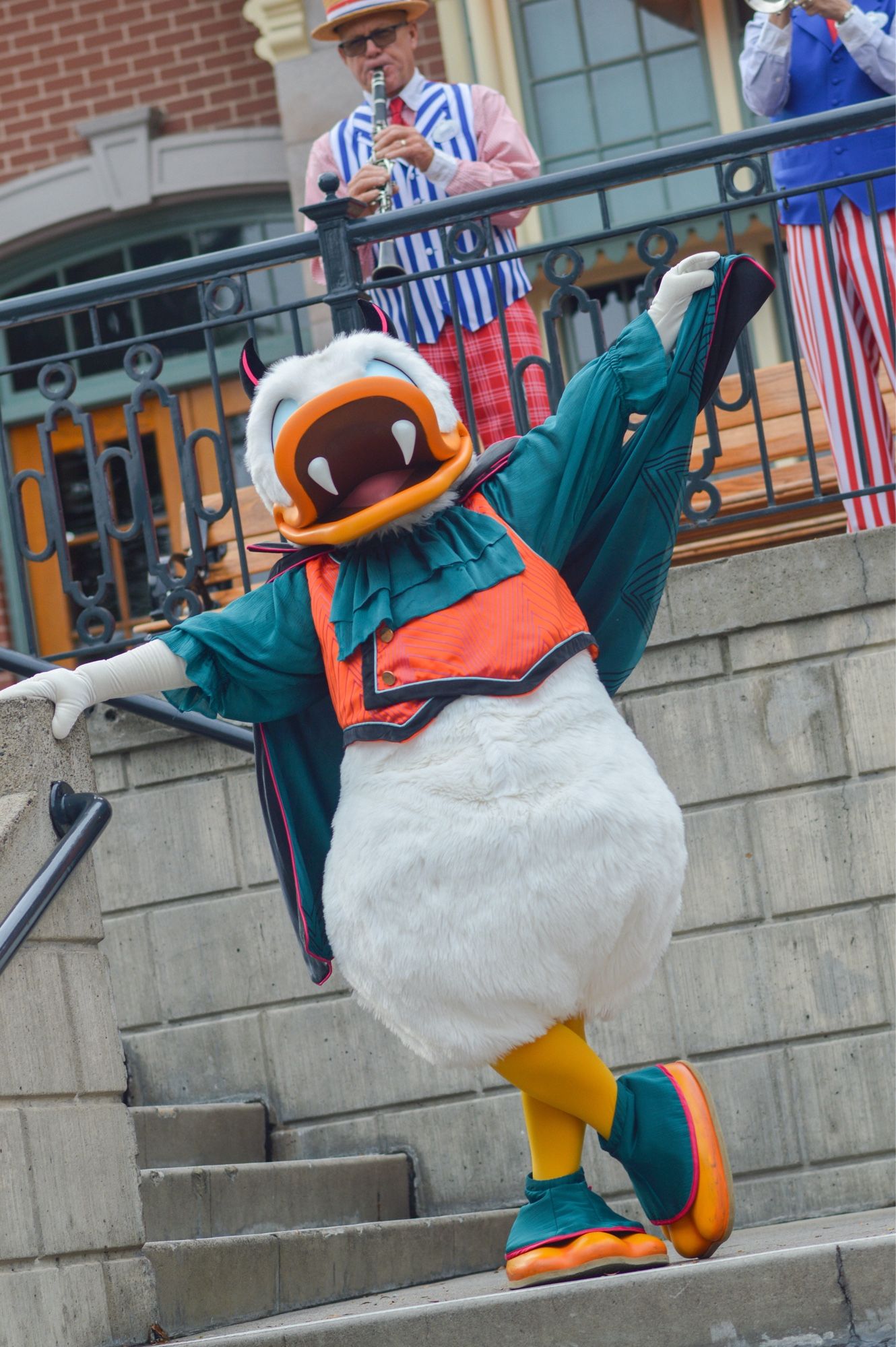 Donald Duck portant des fausses dents, cornes et un costume de vampire bleu marine et orange, il lève sa cape dans les airs