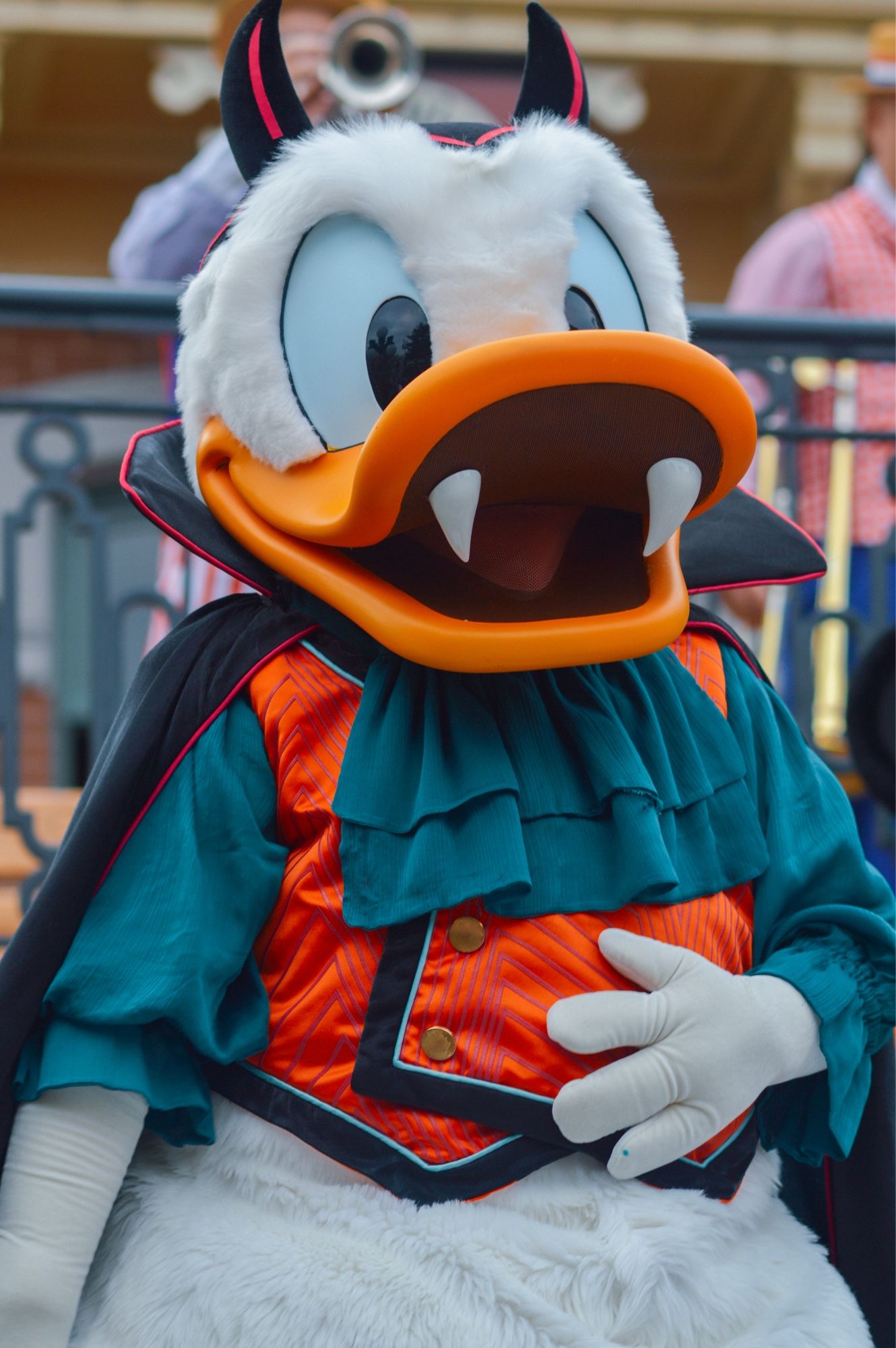 Donald Duck portant des fausses dents, cornes et  un costume de vampire bleu marine et orange