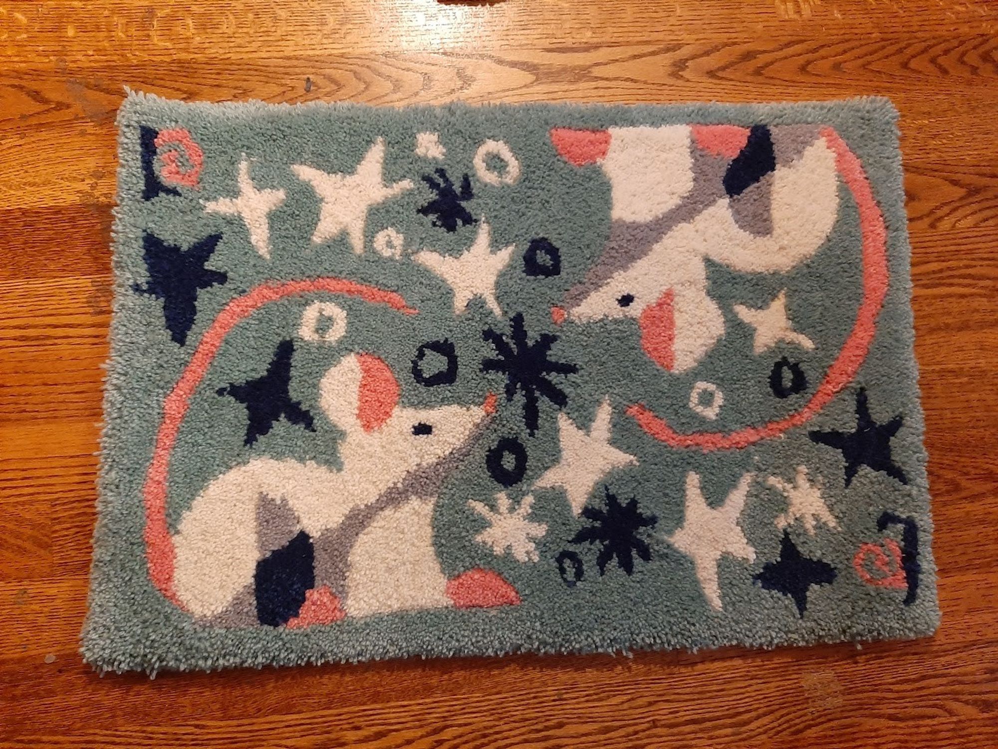 A light green rug with two rats surrounded by white and dark blue stars on it