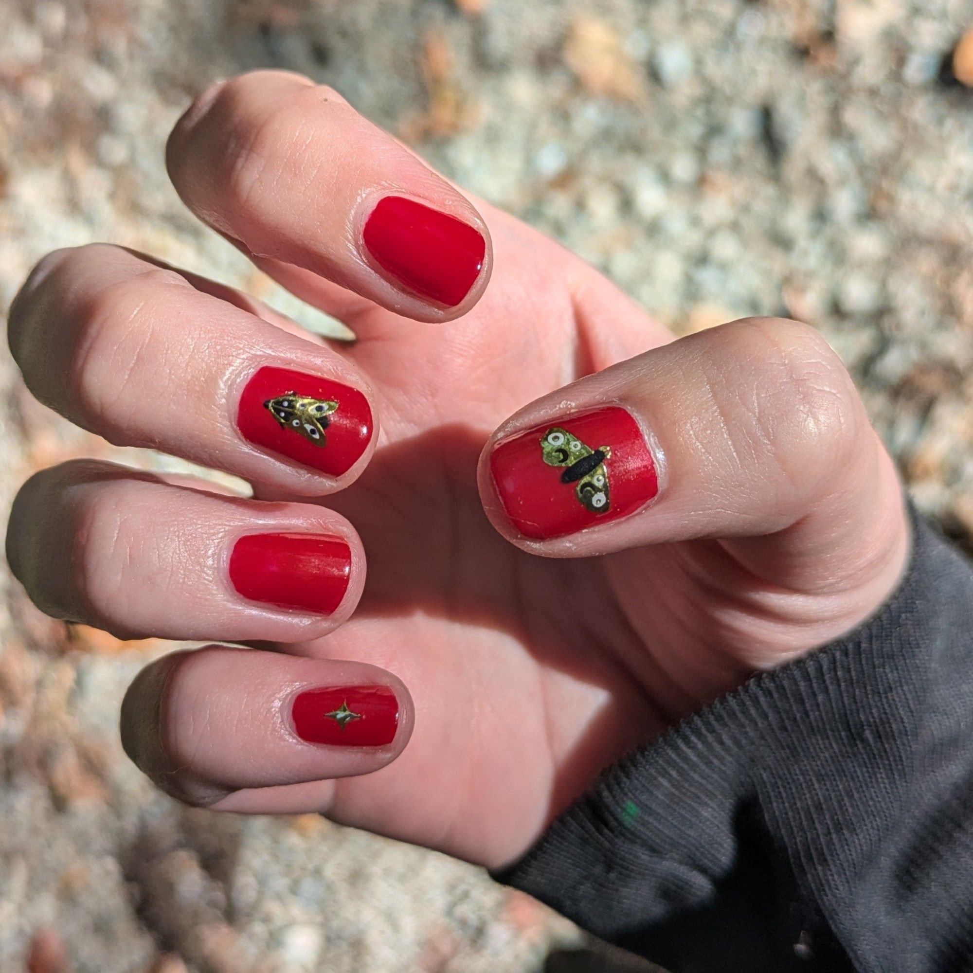 Red nails with shiny gold moths on them