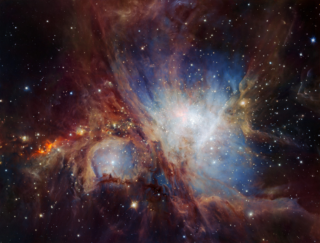 A glowing cloud of gas and dust in deep space. Bright stars shine throughout the scene, surrounded by swirling hues of blue, red, and orange clouds.