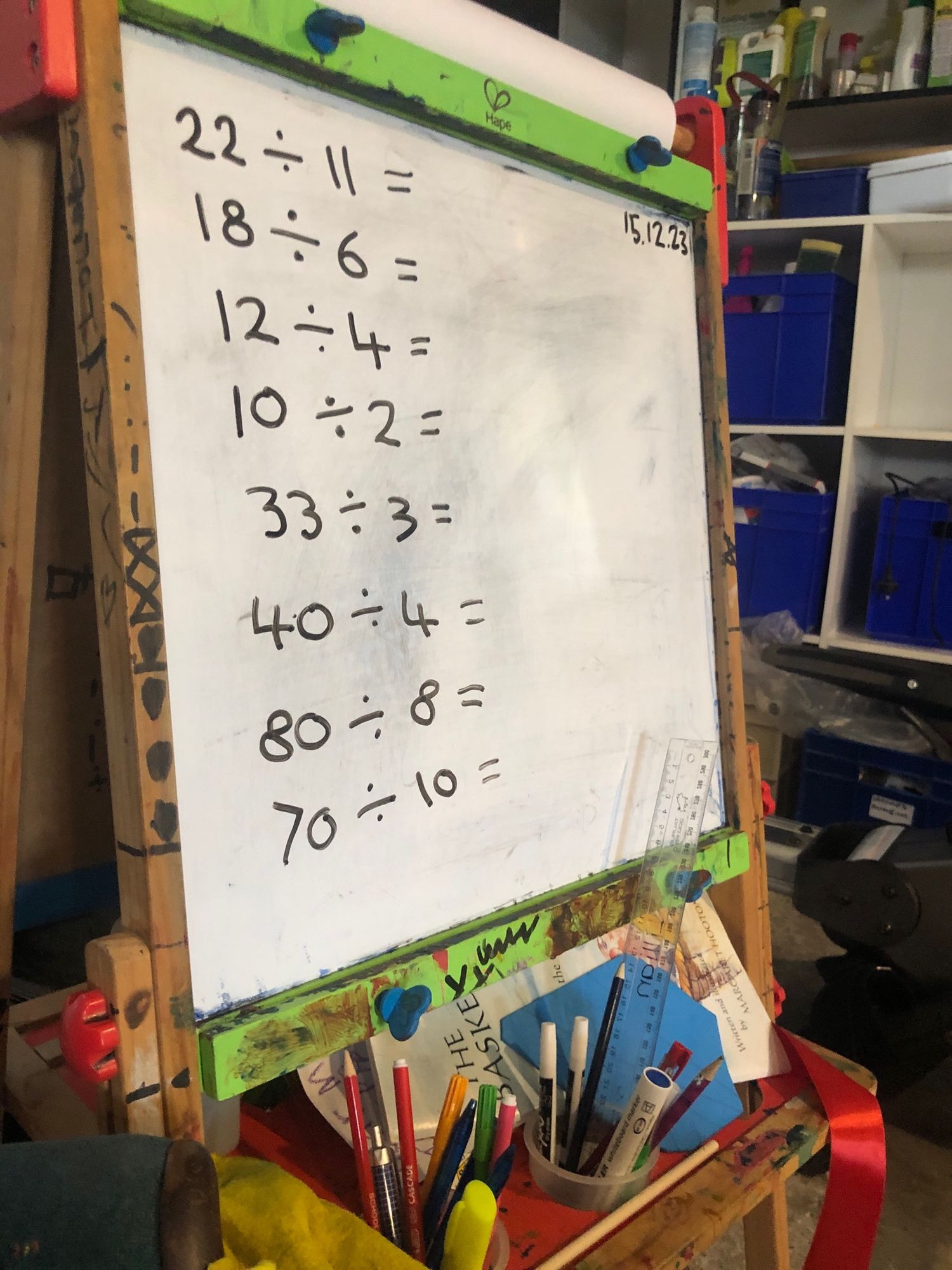 Kids whiteboard with some division exercises written on it.