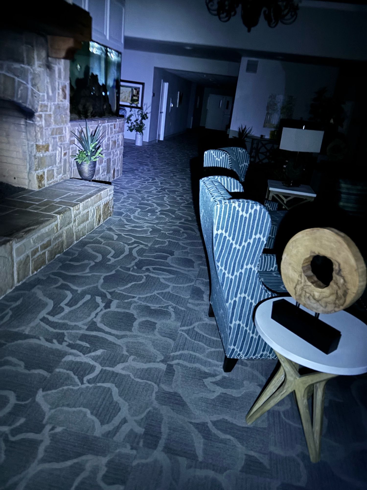 A dark foyer with fireplace and chairs, illuminated with a low power flashlight