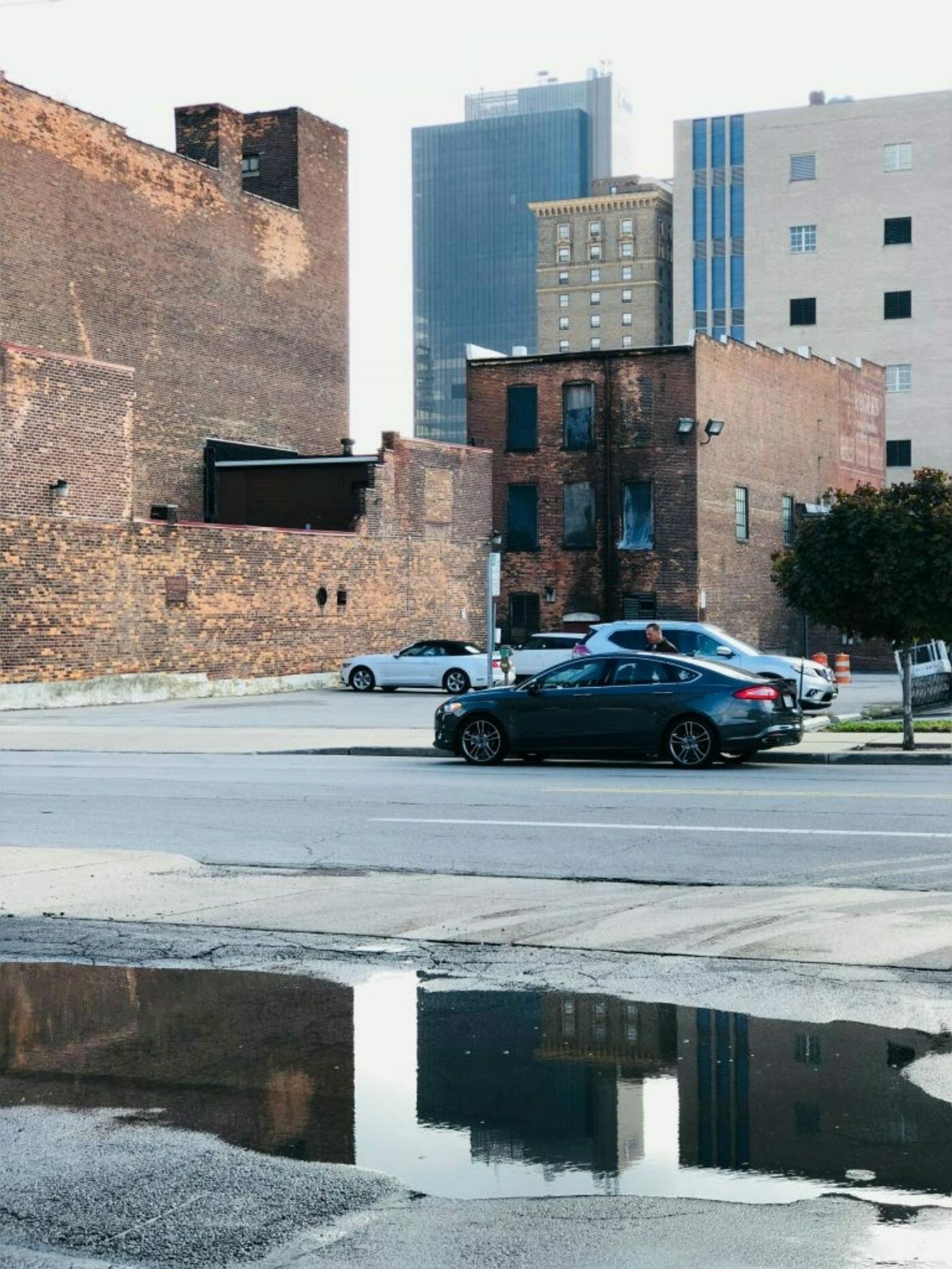 Roadside in city center showing tire tracks leading directly to road-side water runoff.