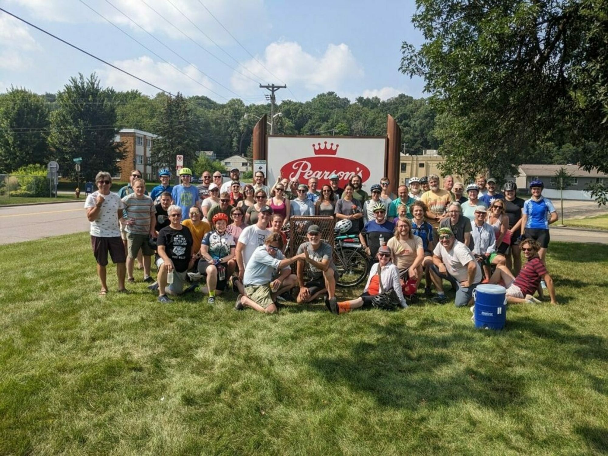 Saint Paul Nut Roll participants pose for a group photo in front of a sign for Pearson's Candy Company