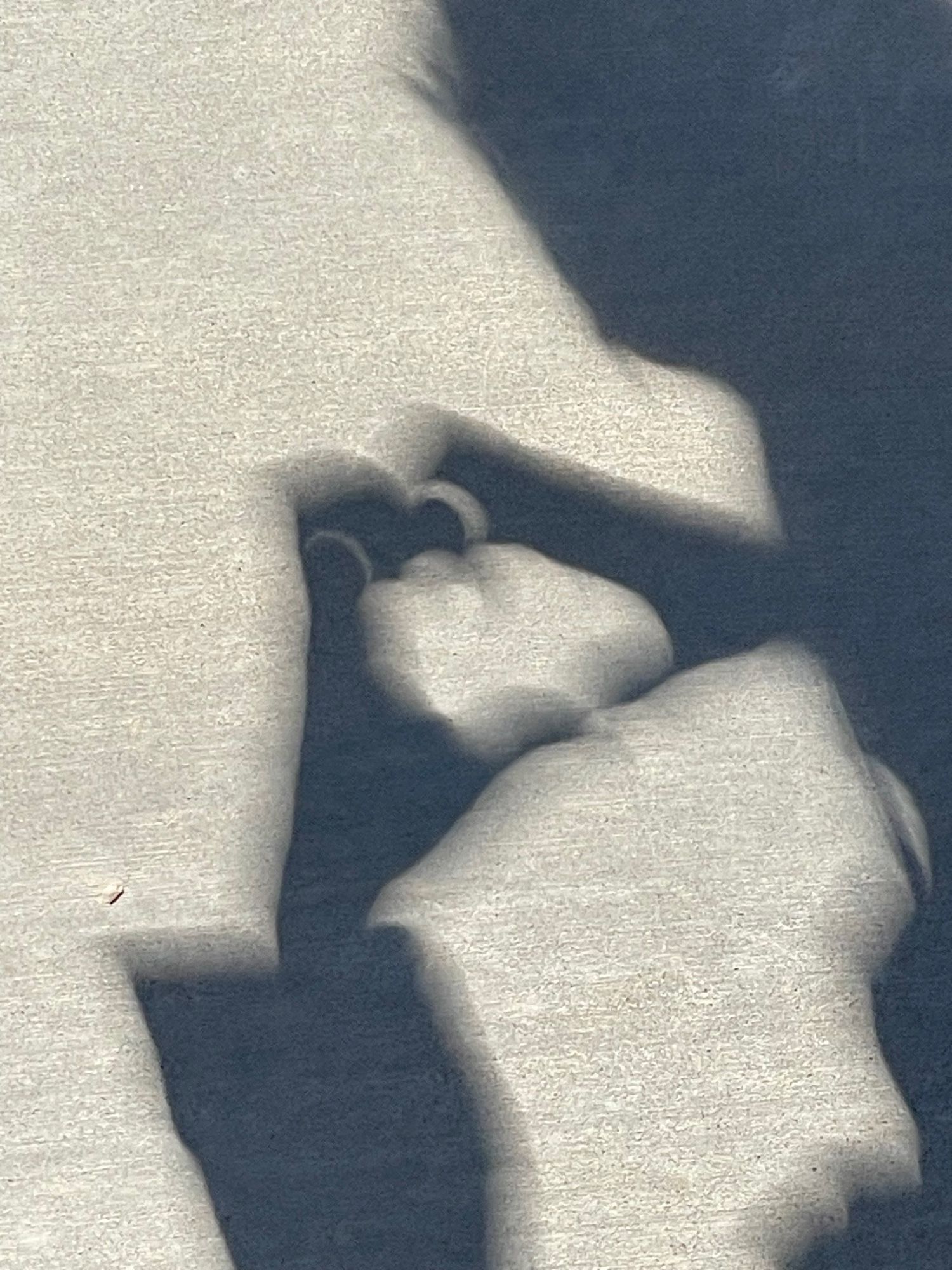 A shadow where the partial annular eclipse looks like eyes and the hands look like a creature.