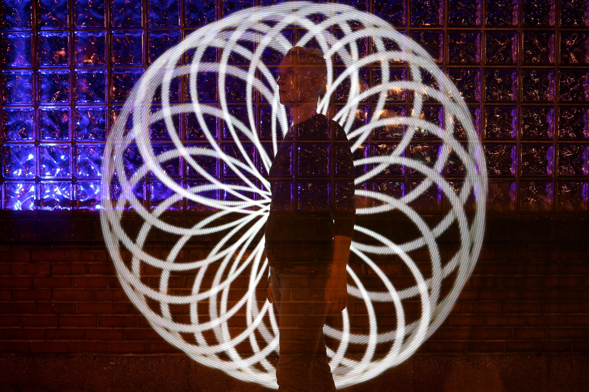 Photograph of Jen’s silhouette standing in front of purple lit glass with spiral lights behind her.