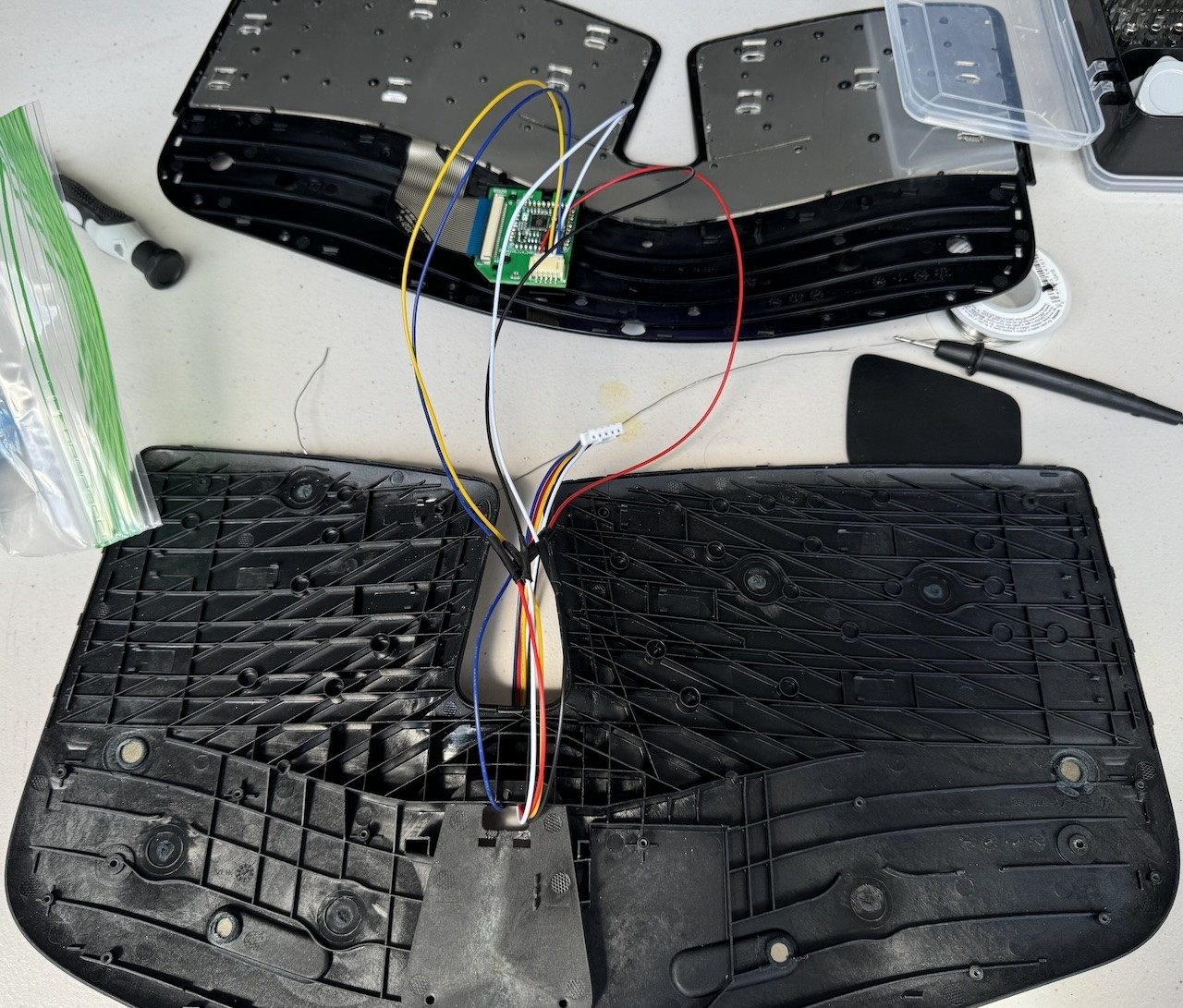 A taken apart keyboard with wires to the custom pcb that contains the Stamp.