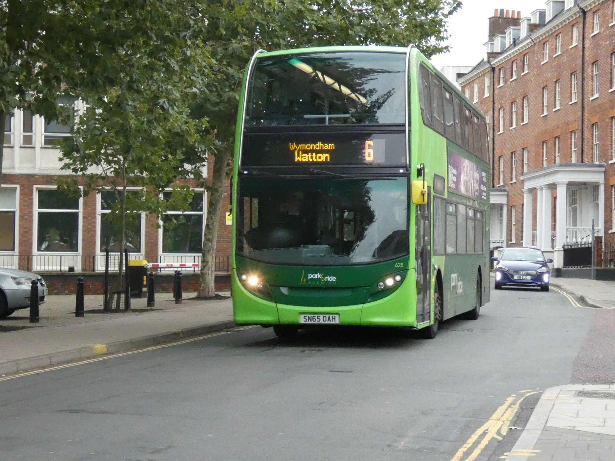 Green double deck bus on city street. Destination screen reads " 6 Watton"