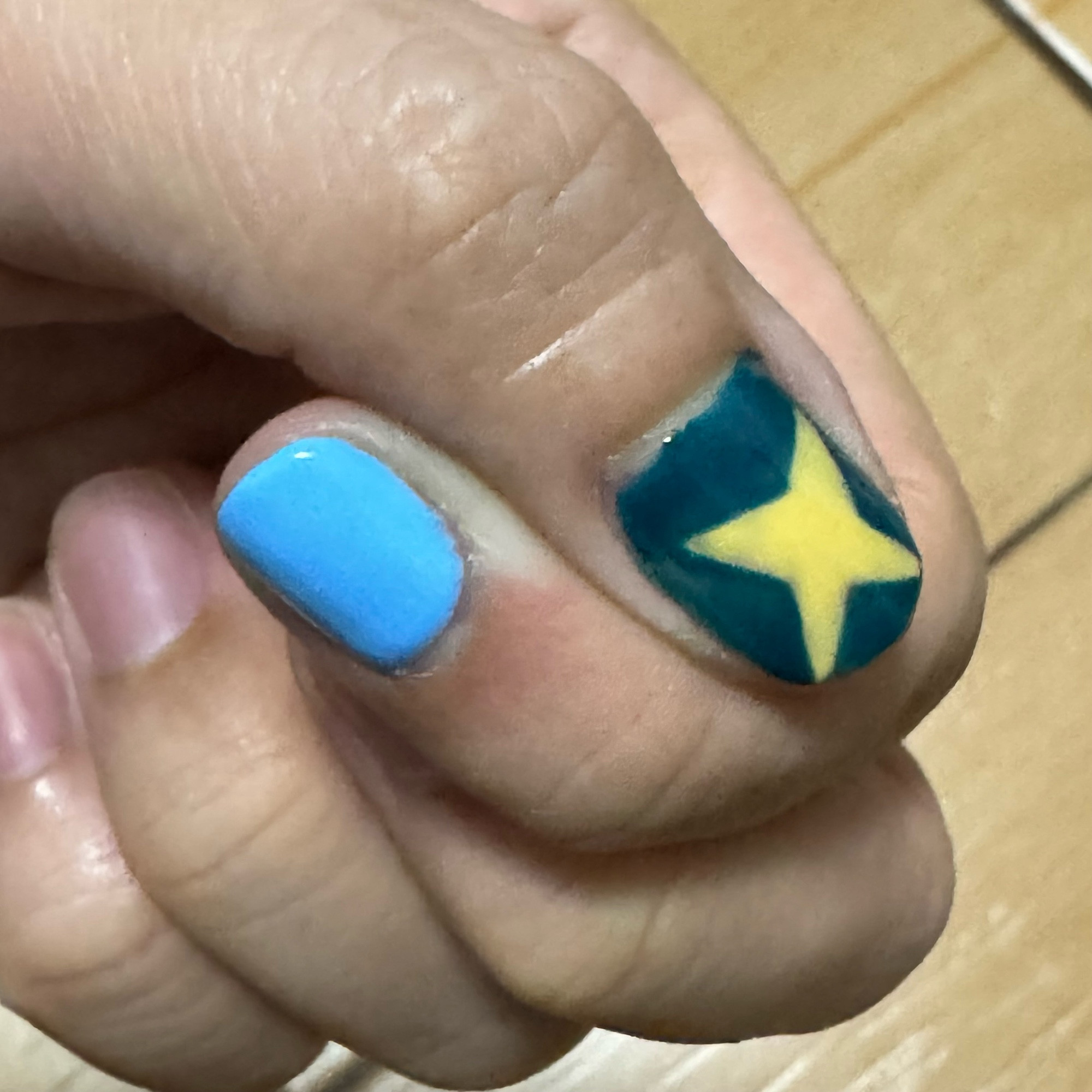 My nails. The pointer nail is sky blue. The thumb has art resembling a yellow star on top of a navy blue.