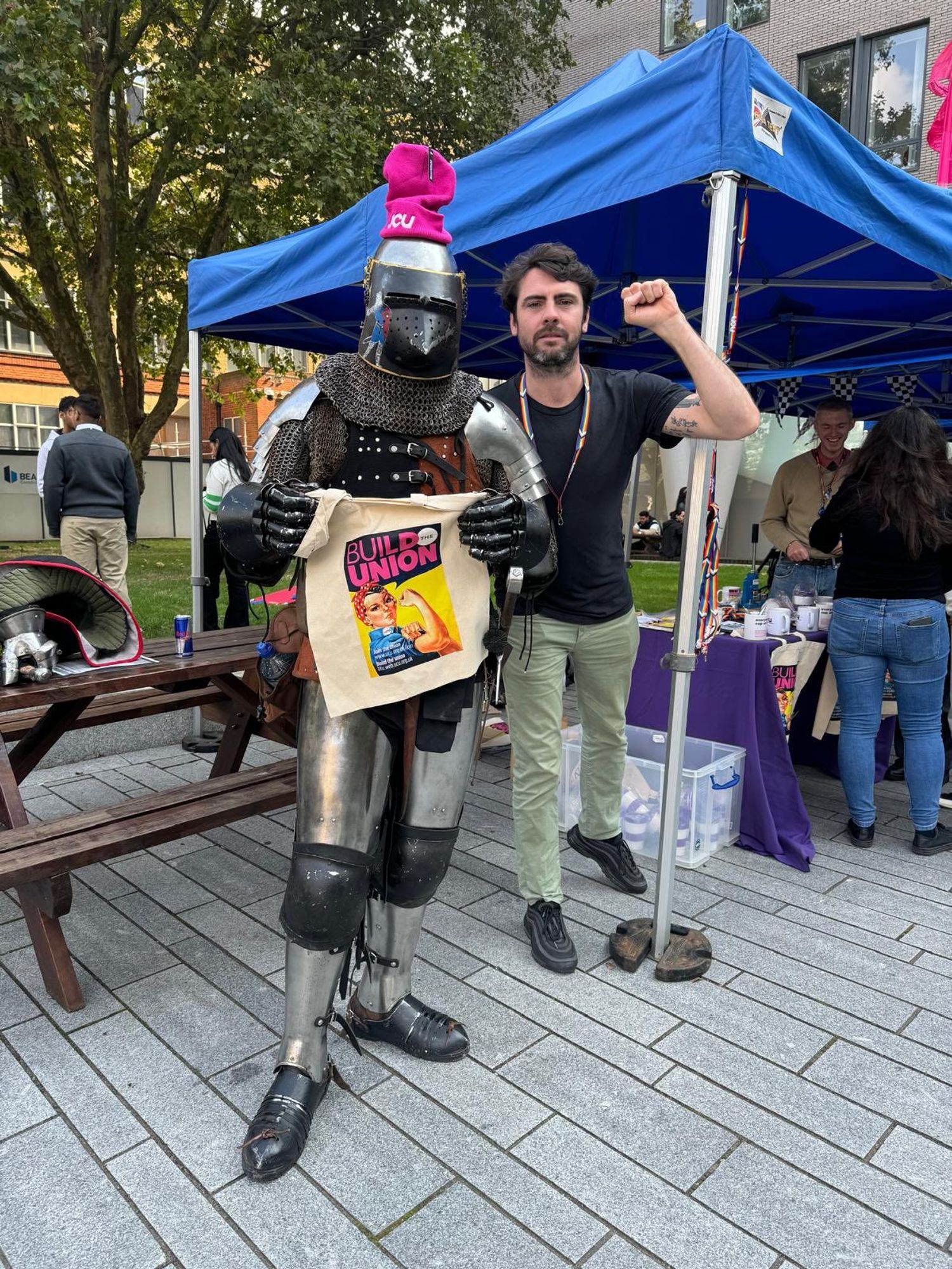 A knight in shining armour holding union swag and wearing a pink UCU beanie