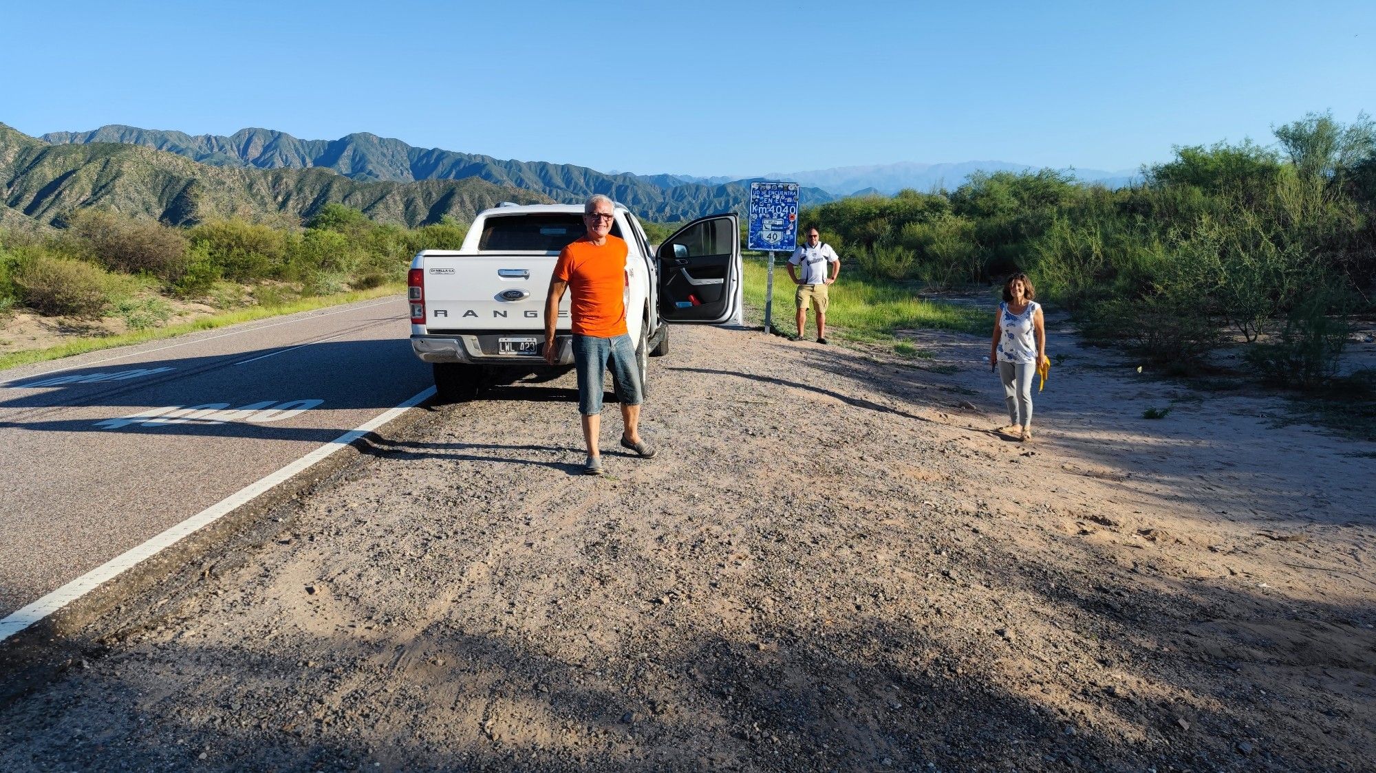 Ein Pickup steht vor einem Schild mit der Aufschrift "Und. se encuentra en el km 4040".
Auf der Straße kann man groß die Markierung 4040 erkennen. Drei Personen posieren vor dem Schild.