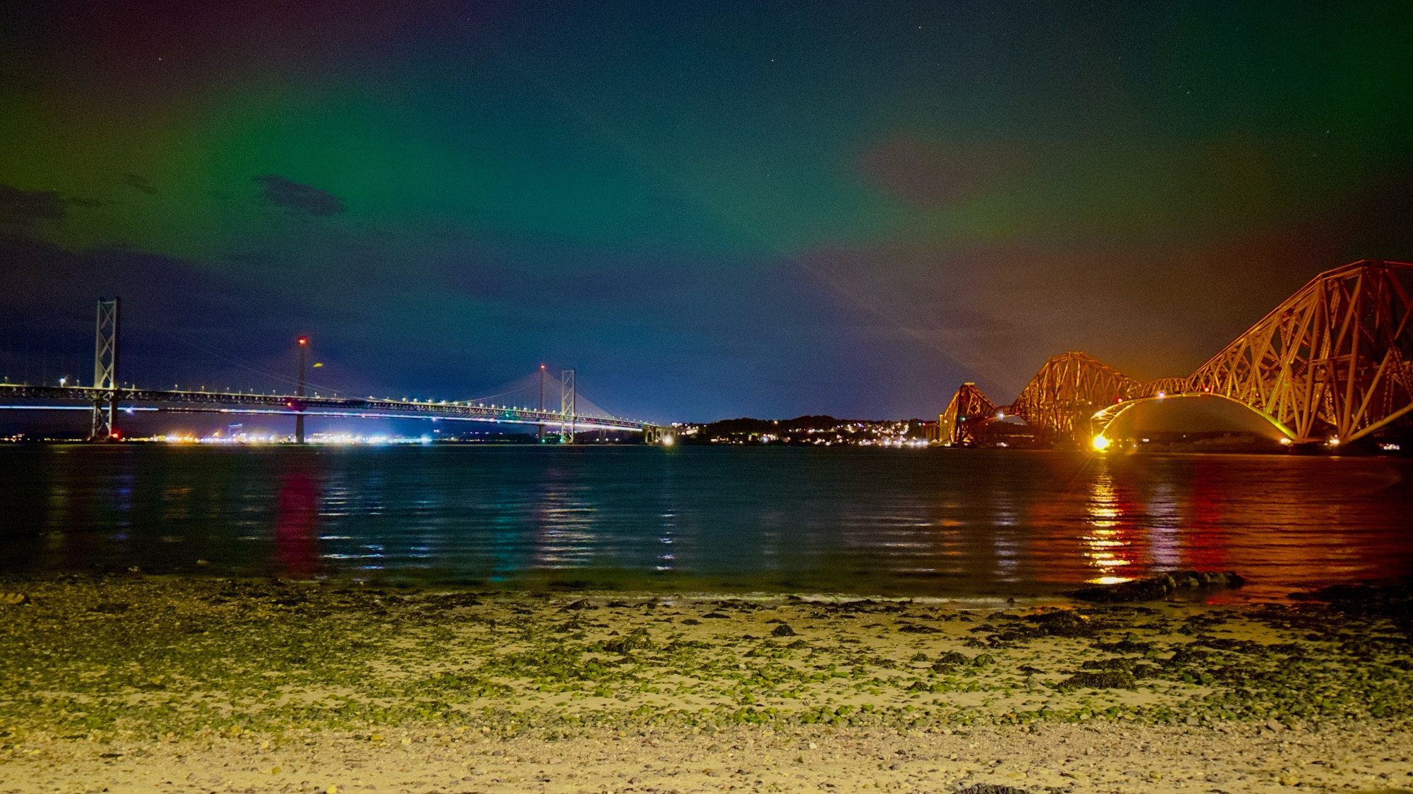 The aurora Borealis over the sea framed by the Forth Bridges