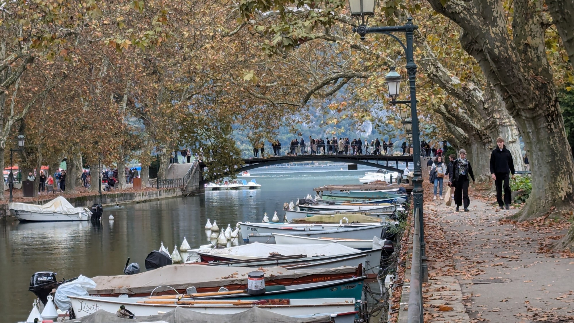 En arrière plan Le pont des amours à Annecy
Au premier plan un canal donnant sur le lac d'Annecy, des bateaux rangés.
Le tout surplombé par le feuillage automnale des arbres.