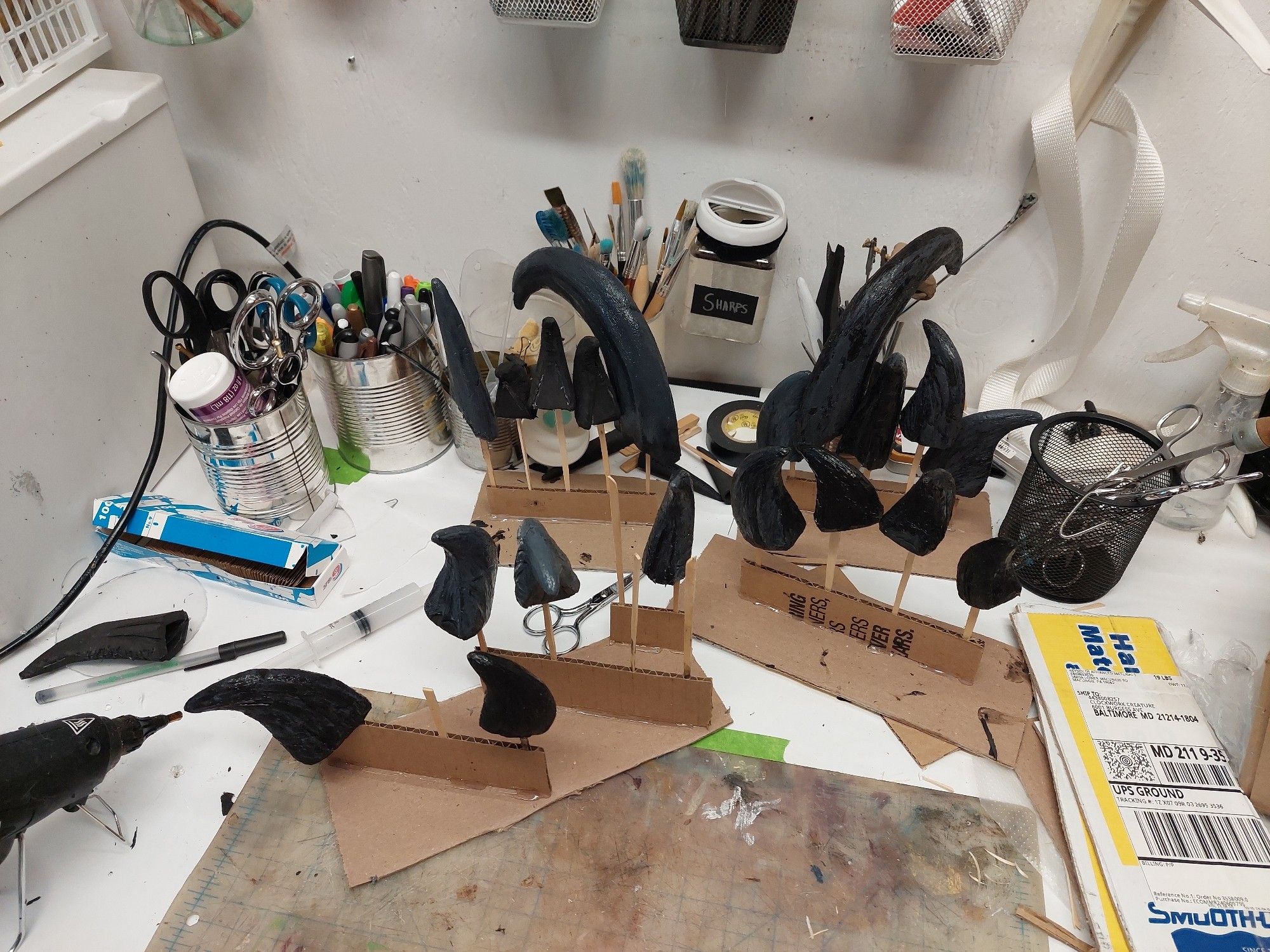 A cluttered work table, featuring a number of large black and grey claws on makeshift stands.