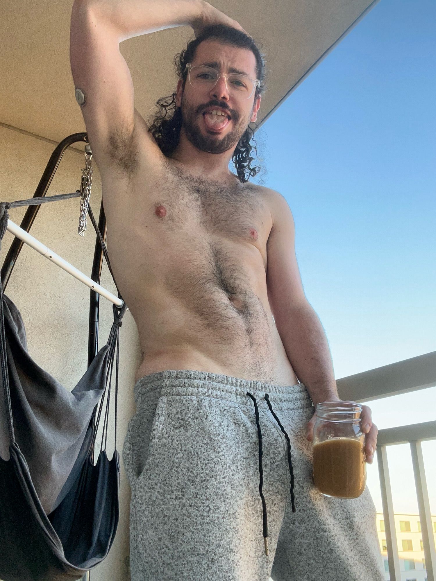 Bauhaus holding a mason jar of coffee with his tongue out and arm raised