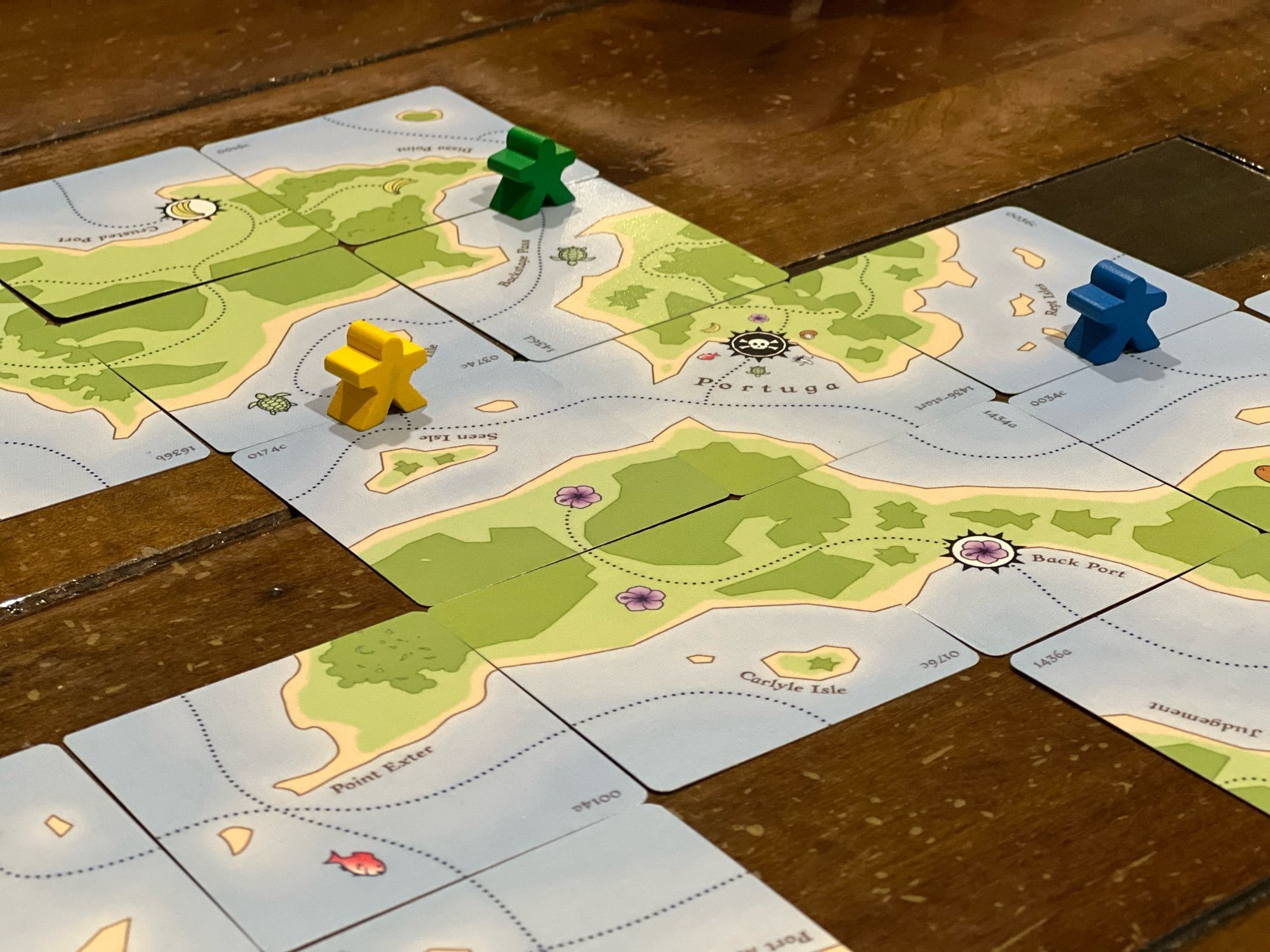 Wooden meeples on a map of islands from square cards.