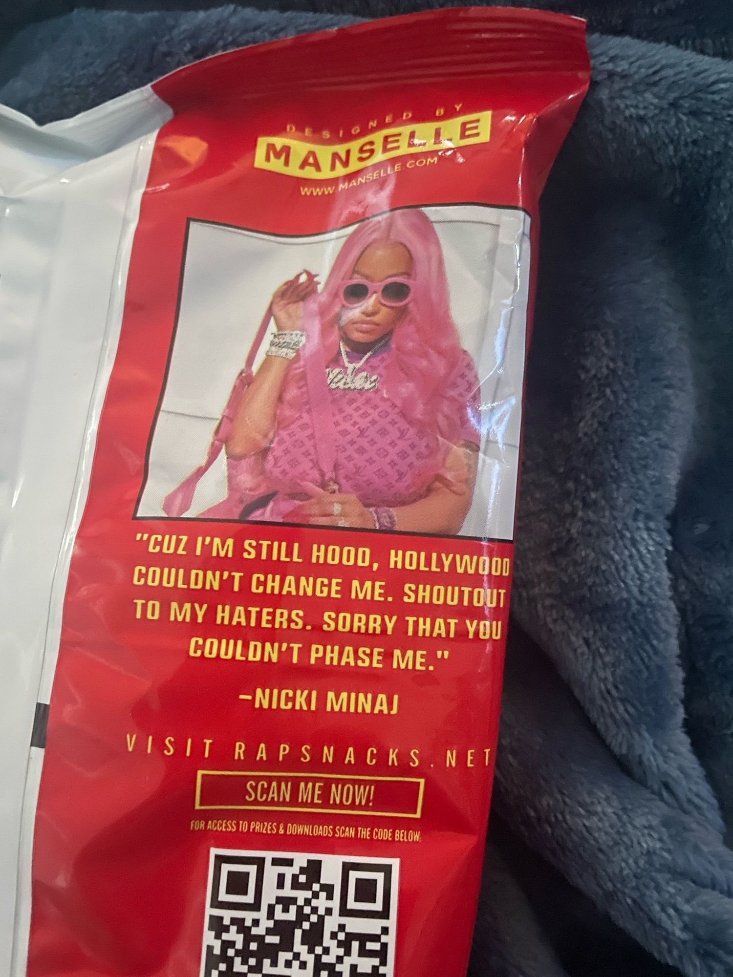 Back of cris packet showing Minaj and a quote from her reading Cuz I’m still hood, hollywood couldn’t change me, shoutout to my haters. Sorry that you couldn’t phase me.