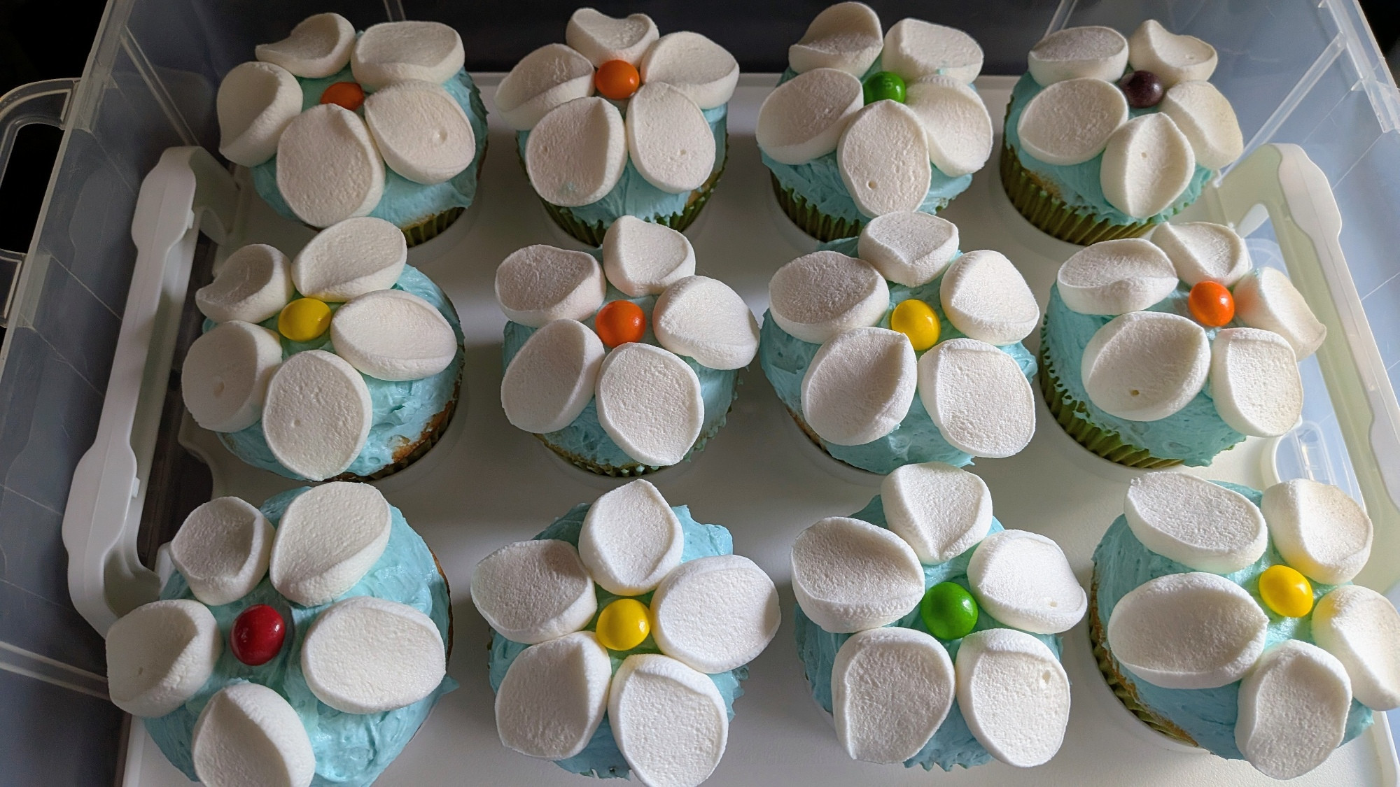 Cupcakes with blue frosting and marshmallows cut to look like petals with a candy in the middle.