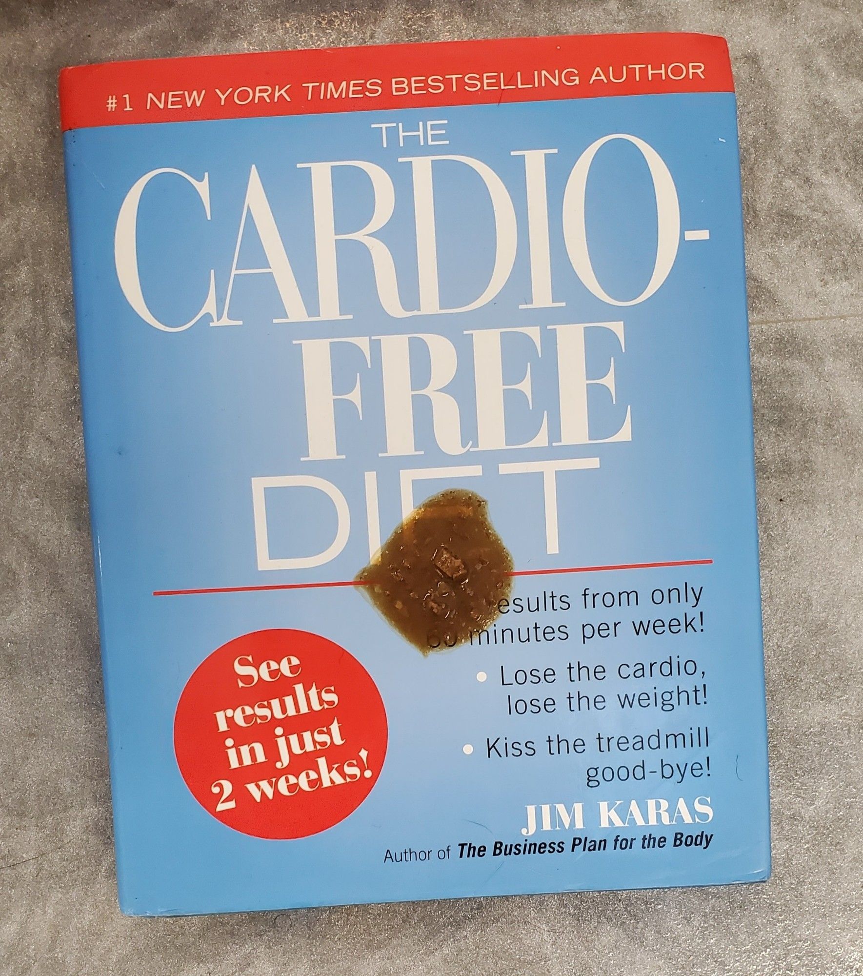 New York Times Best Seller Cardio Free Diet Book with Cat vomit on it. Book has a blue cover and a red circle that reads "See Results in just 2 weeks! " Author is Jim Karas