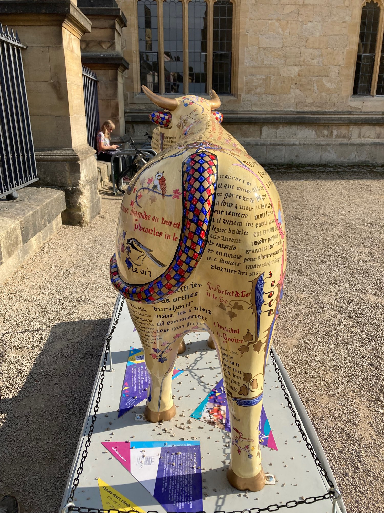 back view of ox sculpture, tail is ref and blue and it’s covered in Latin writing like an ancient manuscript