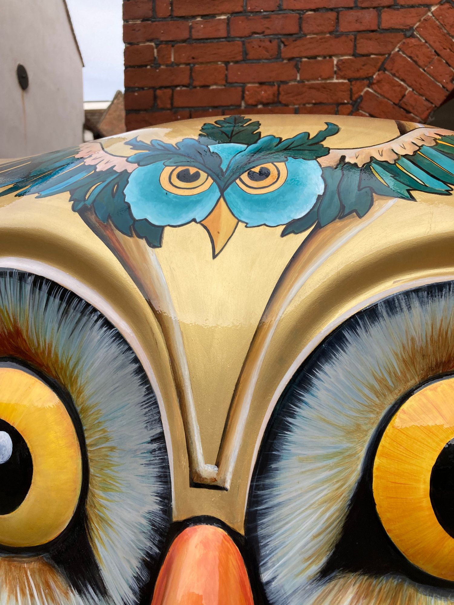 detail of the owl head painted on top of the sculpture's forehead