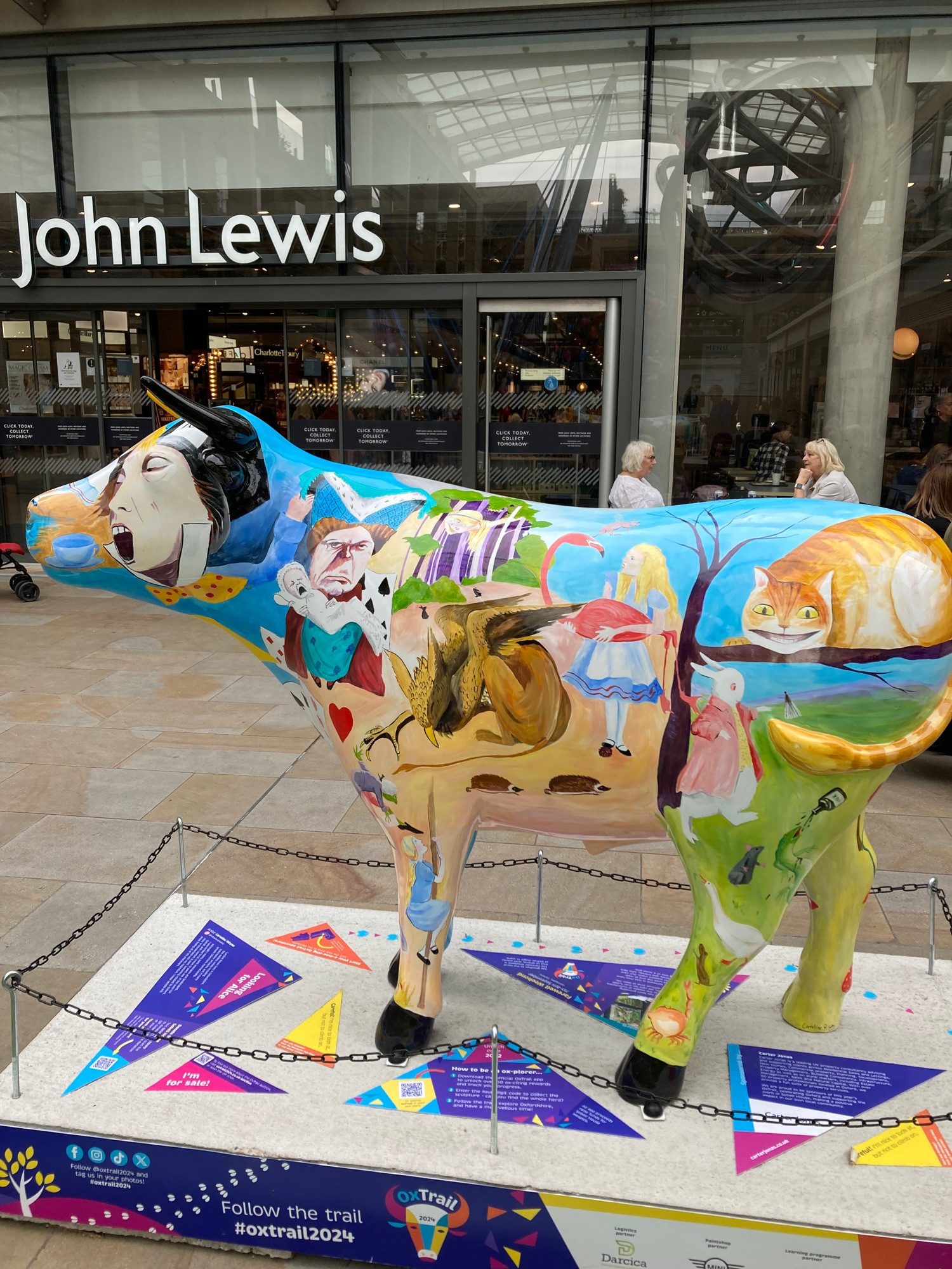 other side view of Ox Sculpture with the Duchess, Cheshire cat and gryphon from Alice in wonderland as well as Alice holding a flamingo