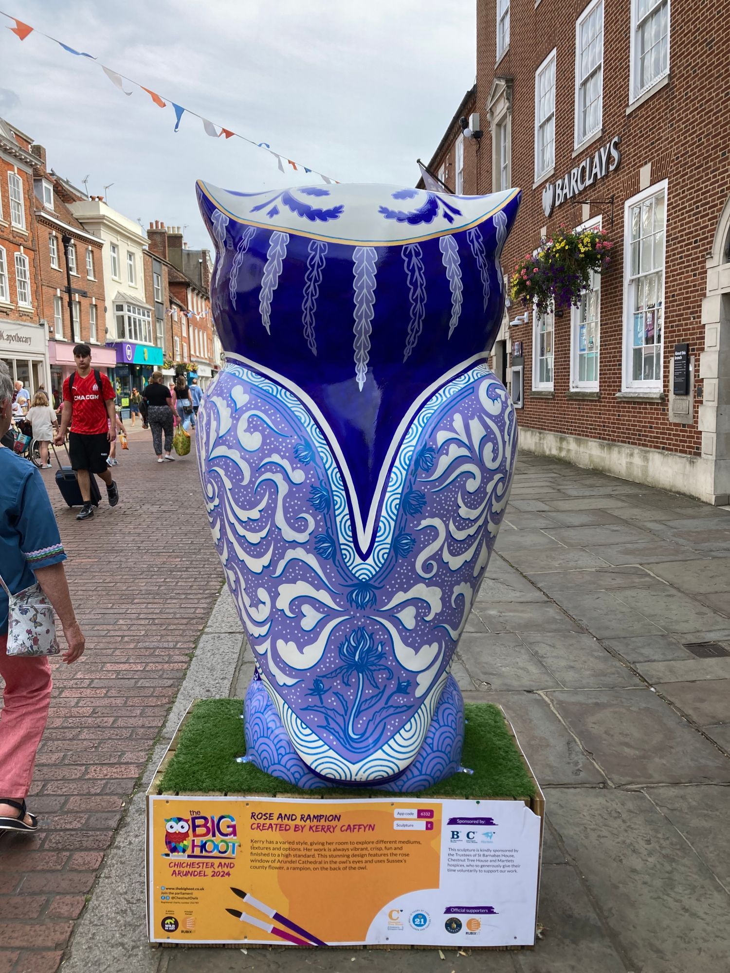 back of arge owl sculpture, it is white with gold beak and claws, the test of it is painted shades of blue, very ornate, like delicate china teaset print.