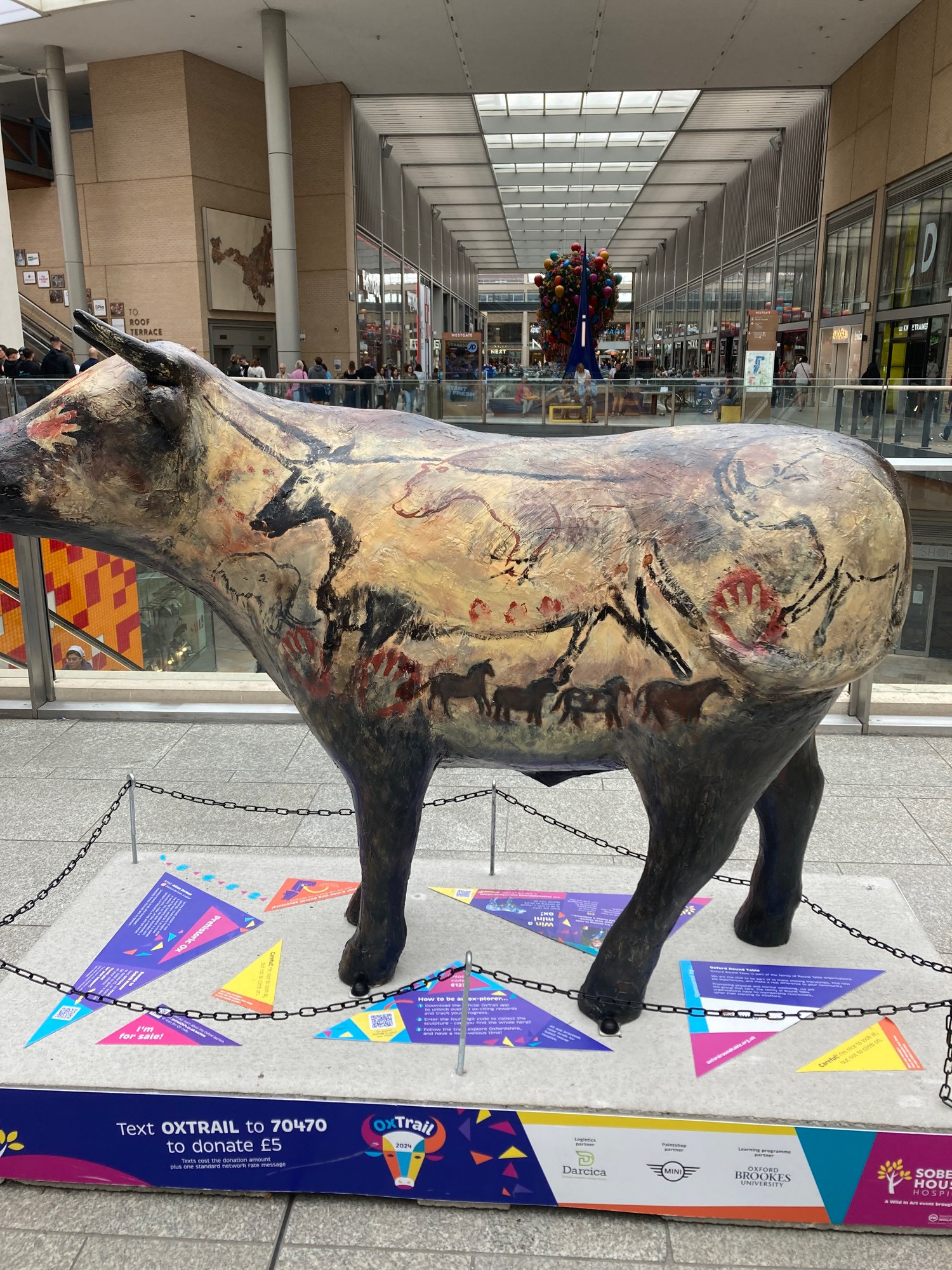 side view of ox sculpture with prehistoric cave like paintings on the side. Looks like cave wall.