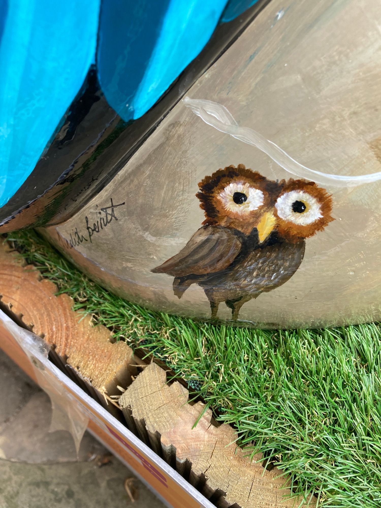 detail of a small owl painted on side of sculpture and the artist's signature