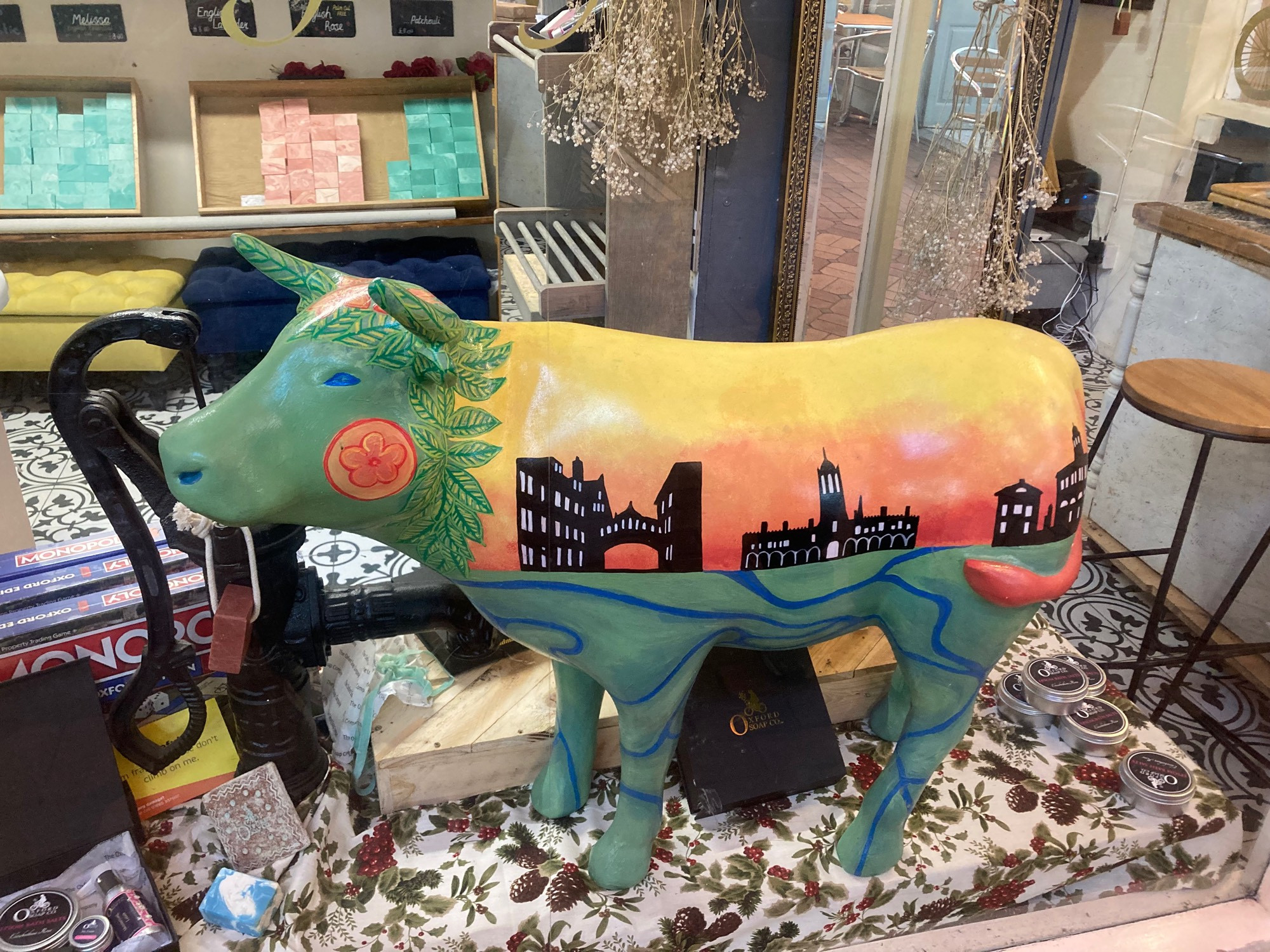 small ox sculpture with green head and legs and sunset above black painted buildings on body