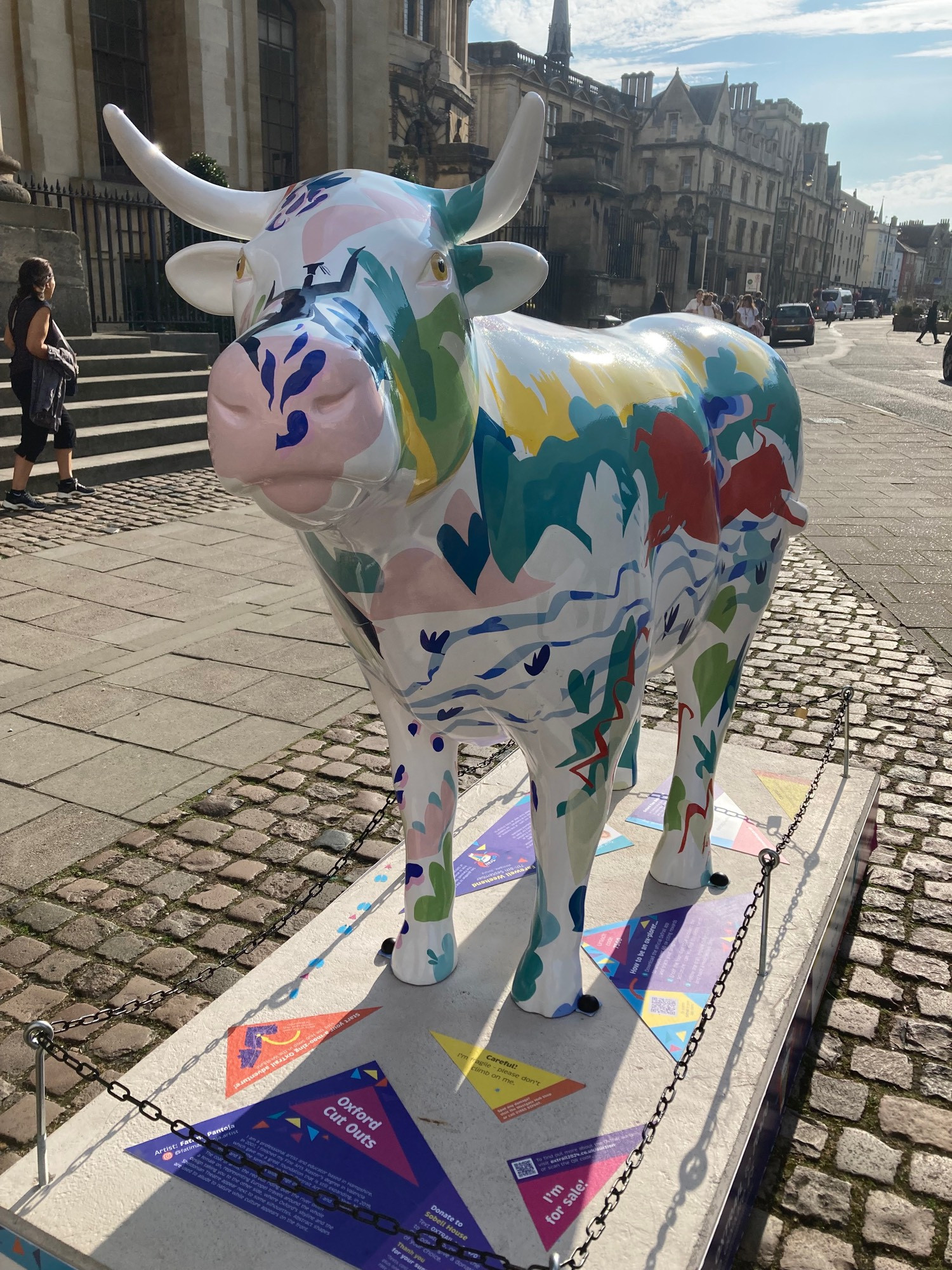 front view of ox sculpture, white with green red yellow and blue markings. Nose is pale pink