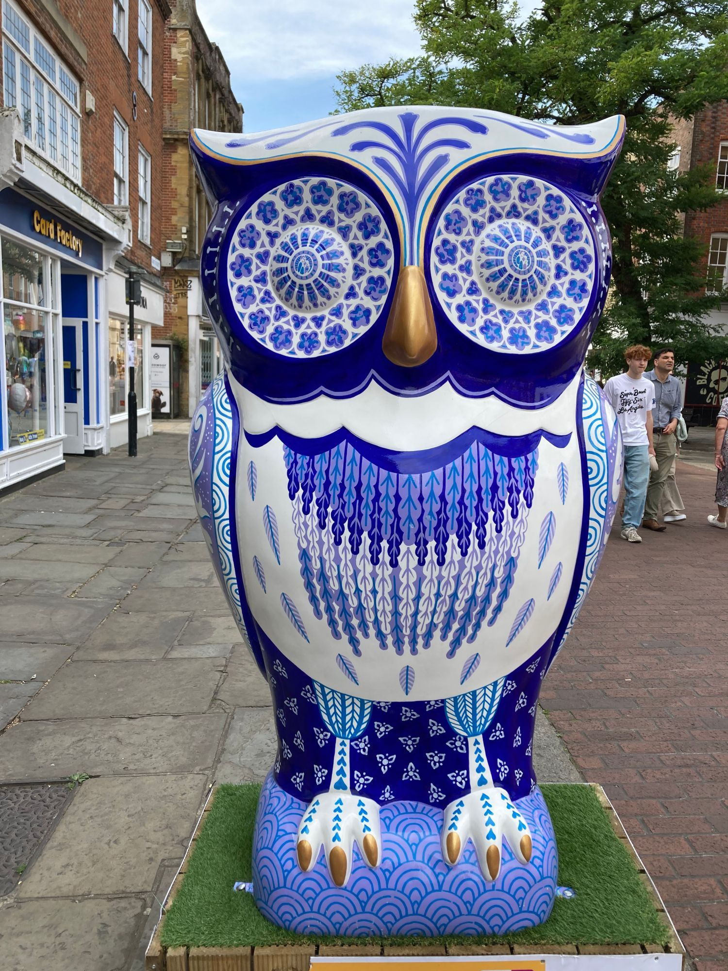 large owl sculpture, it is white with gold beak and claws, the test of it is painted shades of blue, very ornate, like delicate china teaset print.