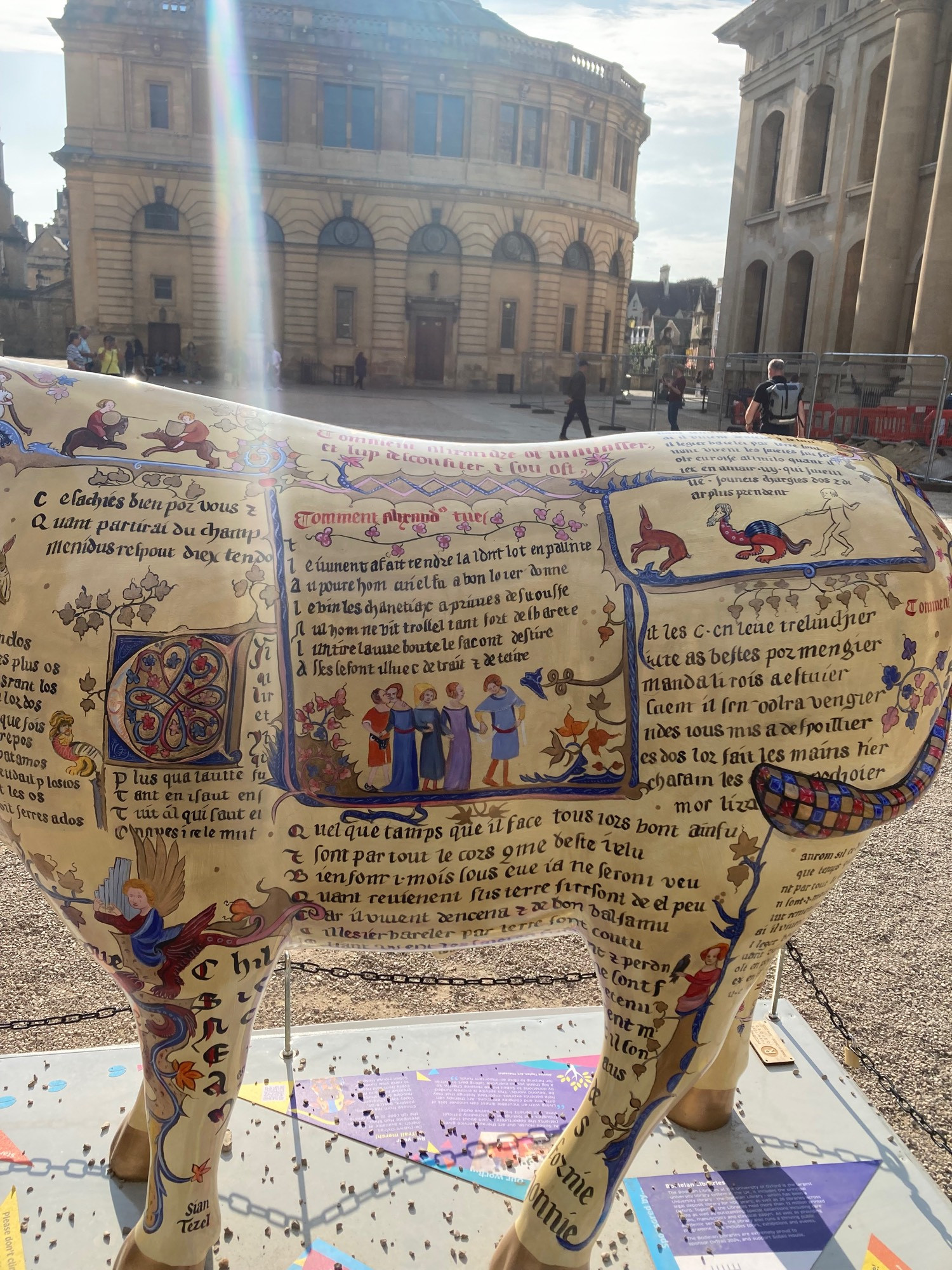 close up side view of ox sculpture. Latin writing and small paintings of people as from a medieval religious text