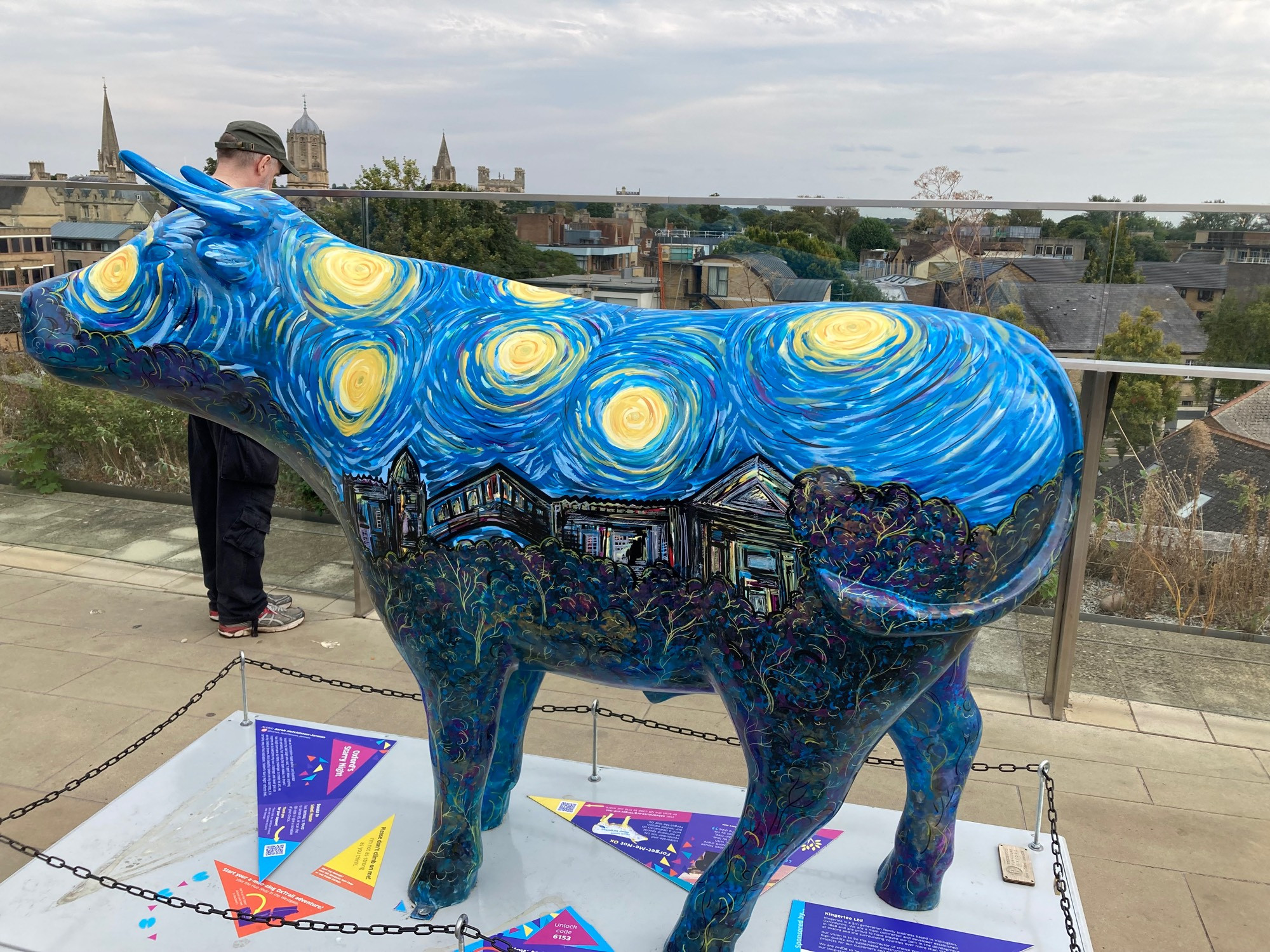 side view ox sculpture in style of starry night by van gogh. deep blue with yellow swirls at top and houses painted below