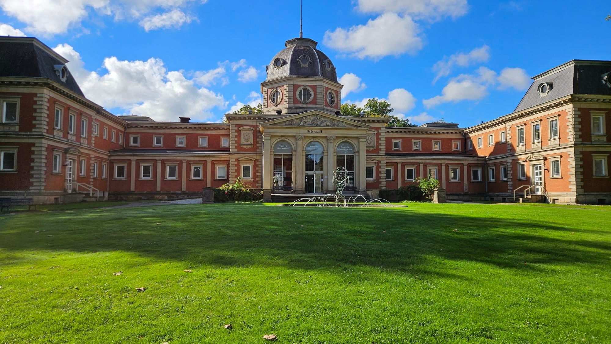 Nog een oud nu van rode steen en met 2 zijvleugels. Ook hier in het midden een pompeus deel, wat tevens de ingang is. Op dat deel een hoge koepel met een zwart dak. Ervoor een groot grasveld met een fontein met kunstwerk erin, water van de fontein komt niet zo heel hoogm