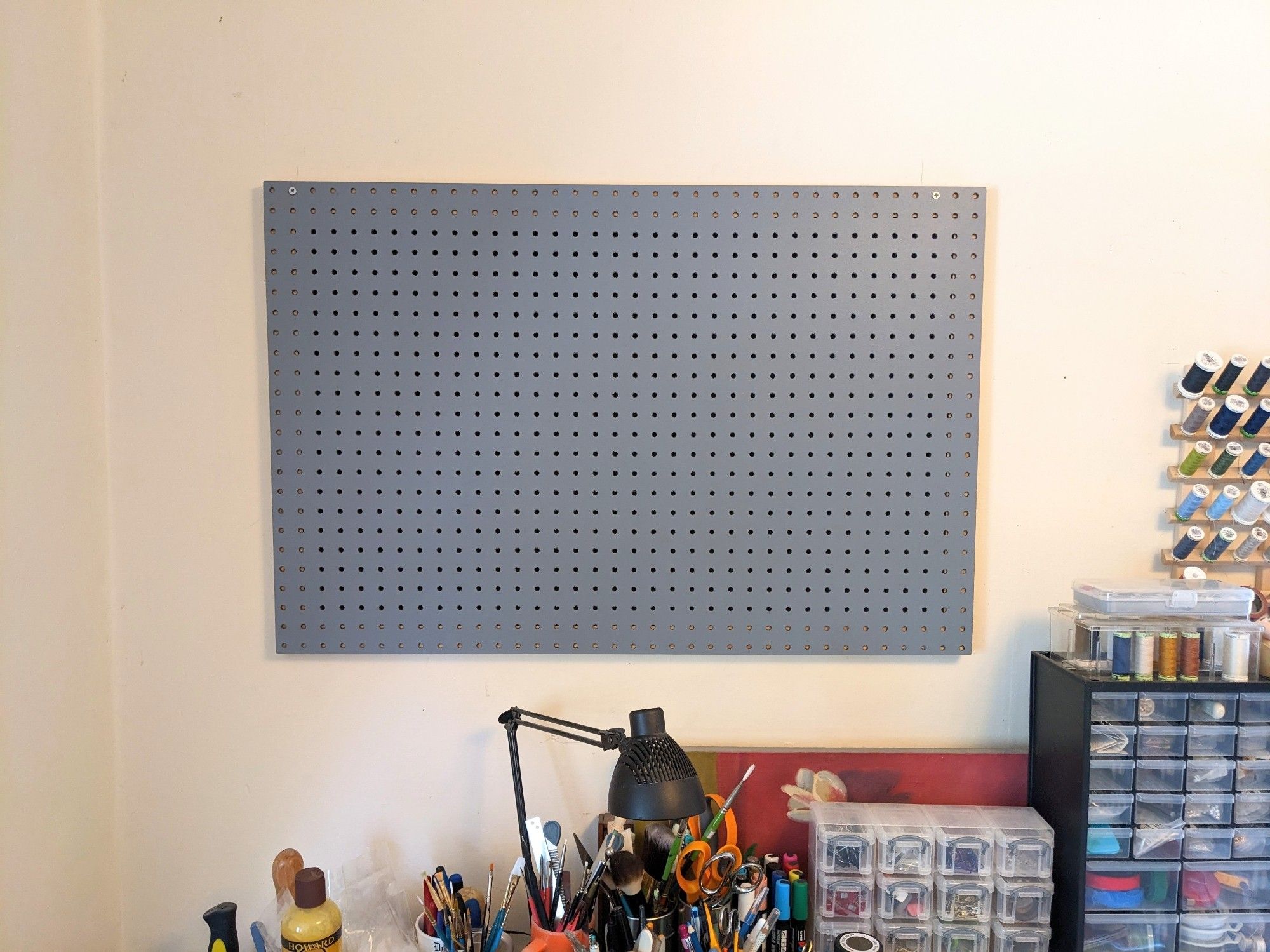 Photo of a homemade 24x36" pegboard organizer installed on the wall of my workroom. The pegboard is empty.