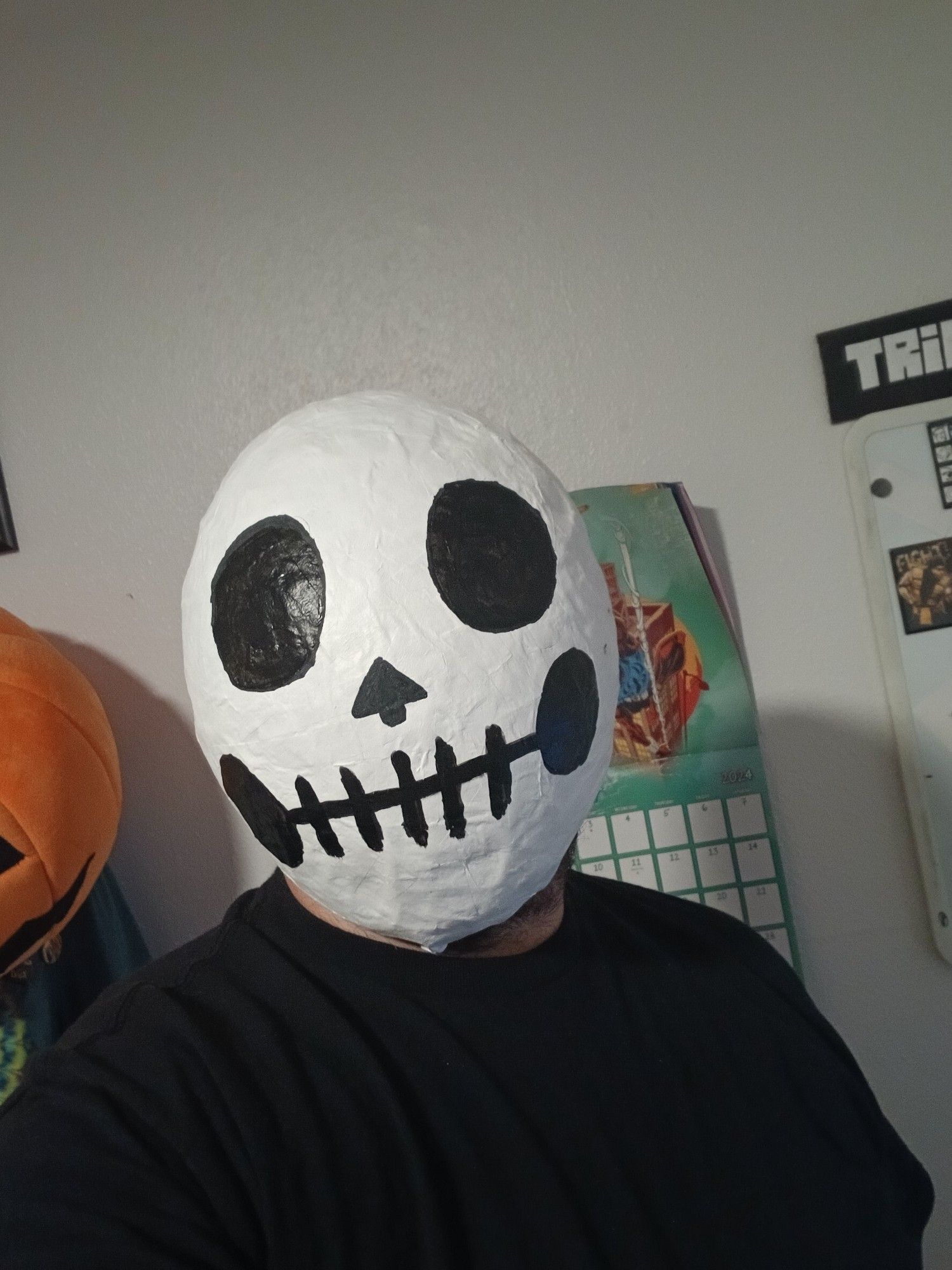 A photo of me wearing a paper mache mask that's been painted like a cartoonish skull.