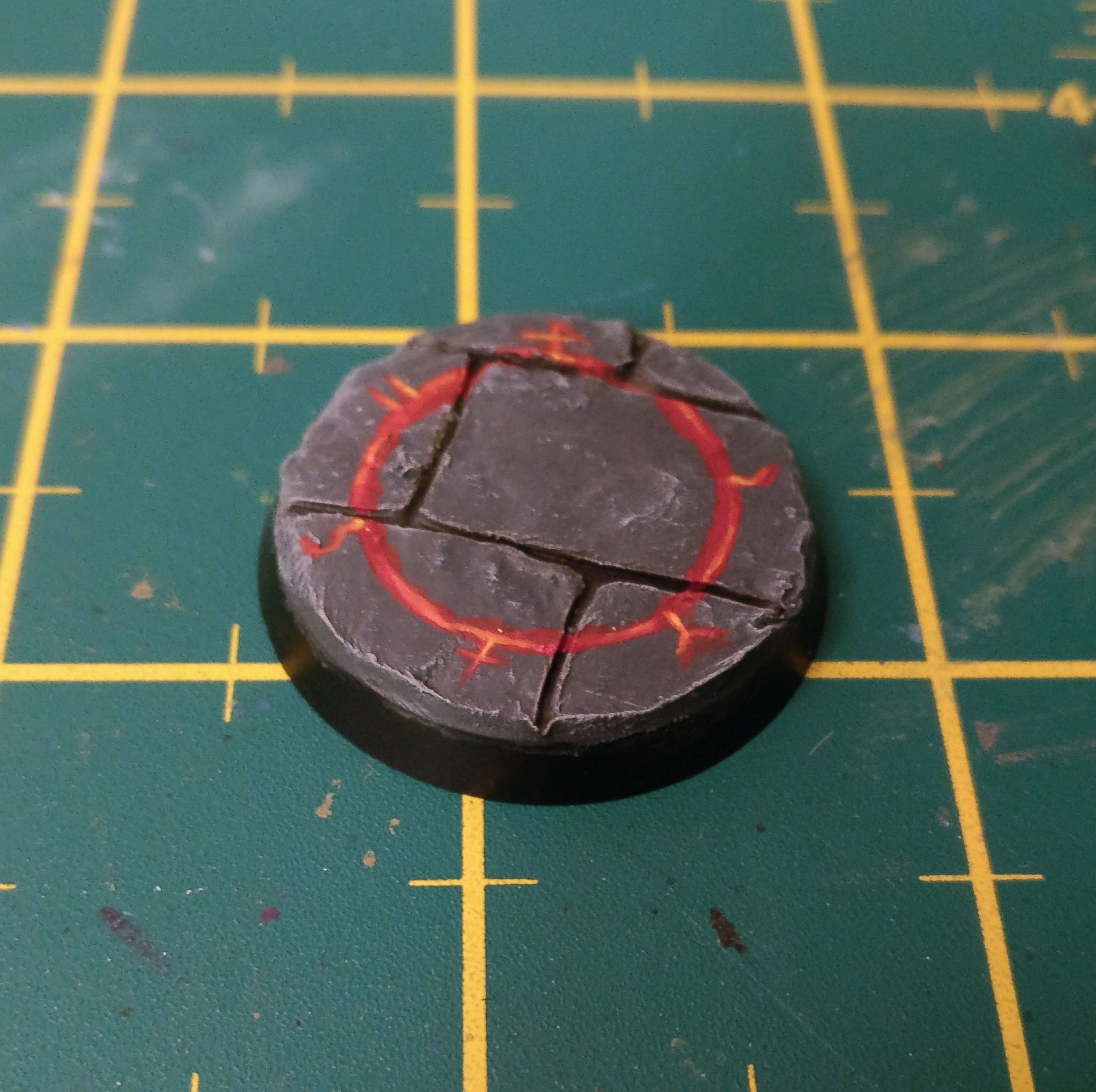 Base for a sorceror model. Greenstuff flagstones painted grey, with a red and yellow magic circle on top.