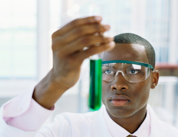 Photo of a black scientist holding a test tube with green liquid on it