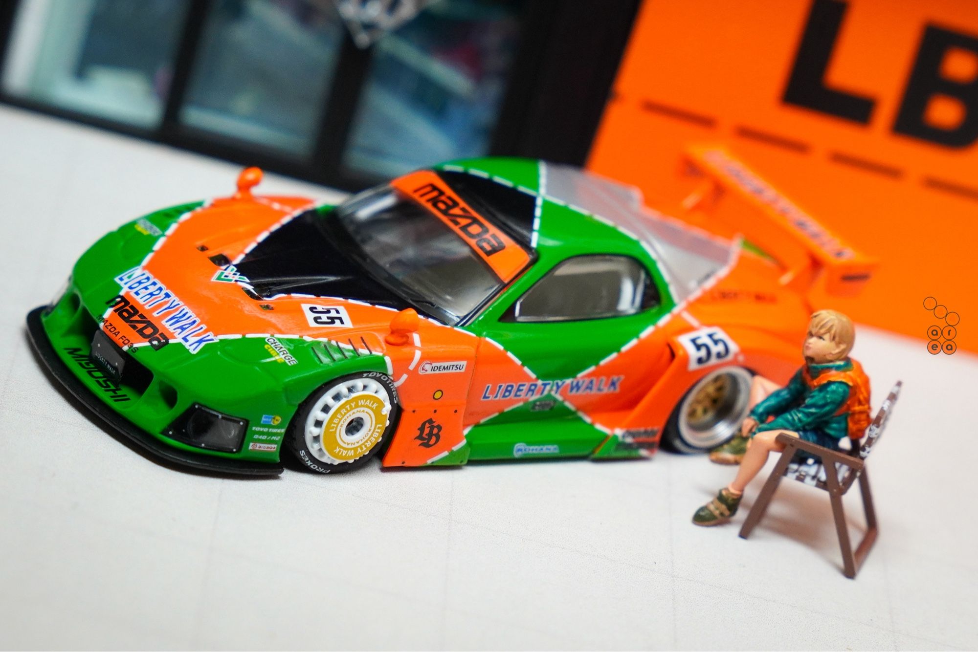 A girl sit beside Mazda RX-7 FD3S, LB-Super Silhouette Renown livery by iNNO64 in 1:64 scale with 1:64 figure on AREA 164