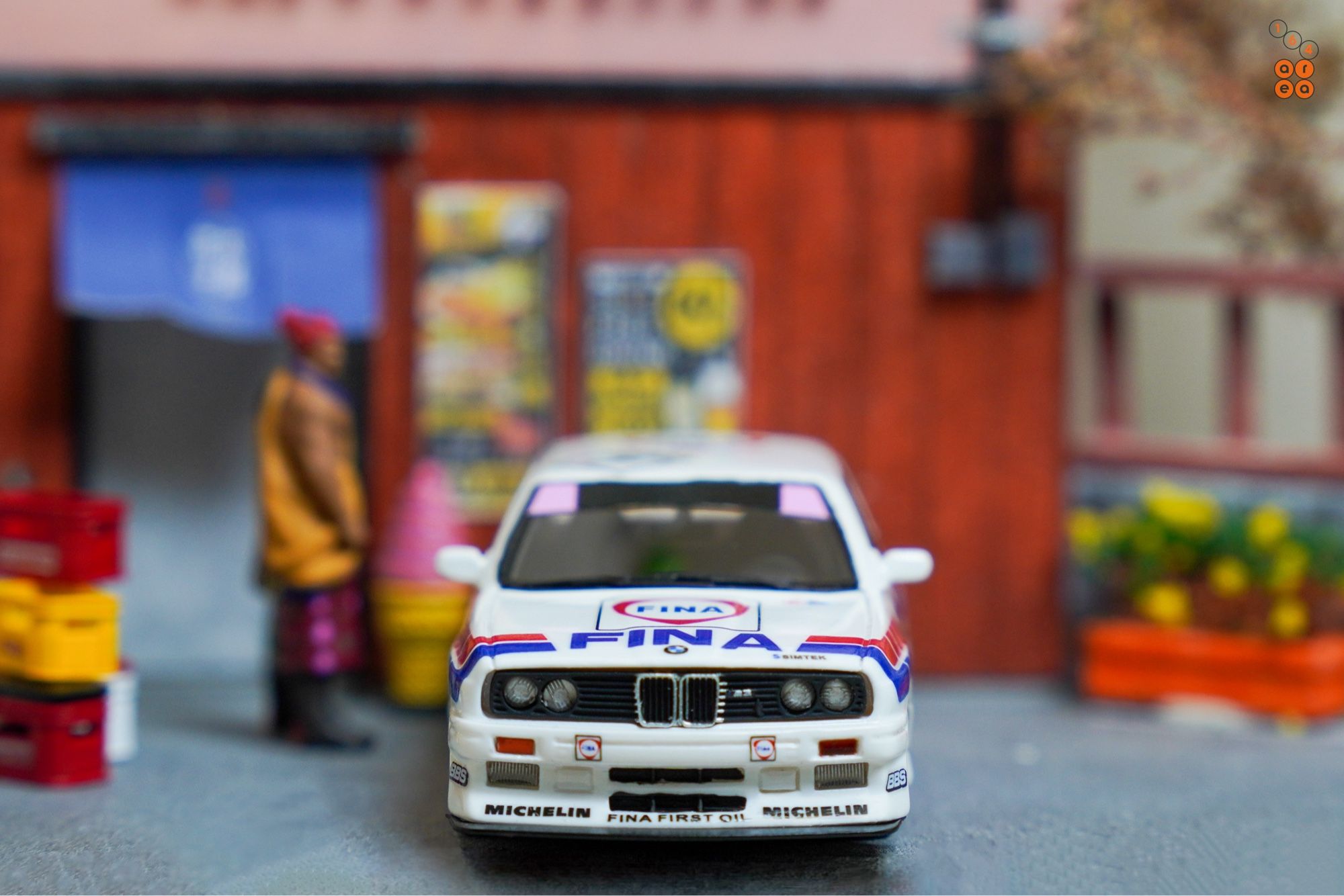 A front side of BMW E30 M3, FINA First Oil livery by ScaleMini in 1:64 scale with 1:64 figures on AREA 164